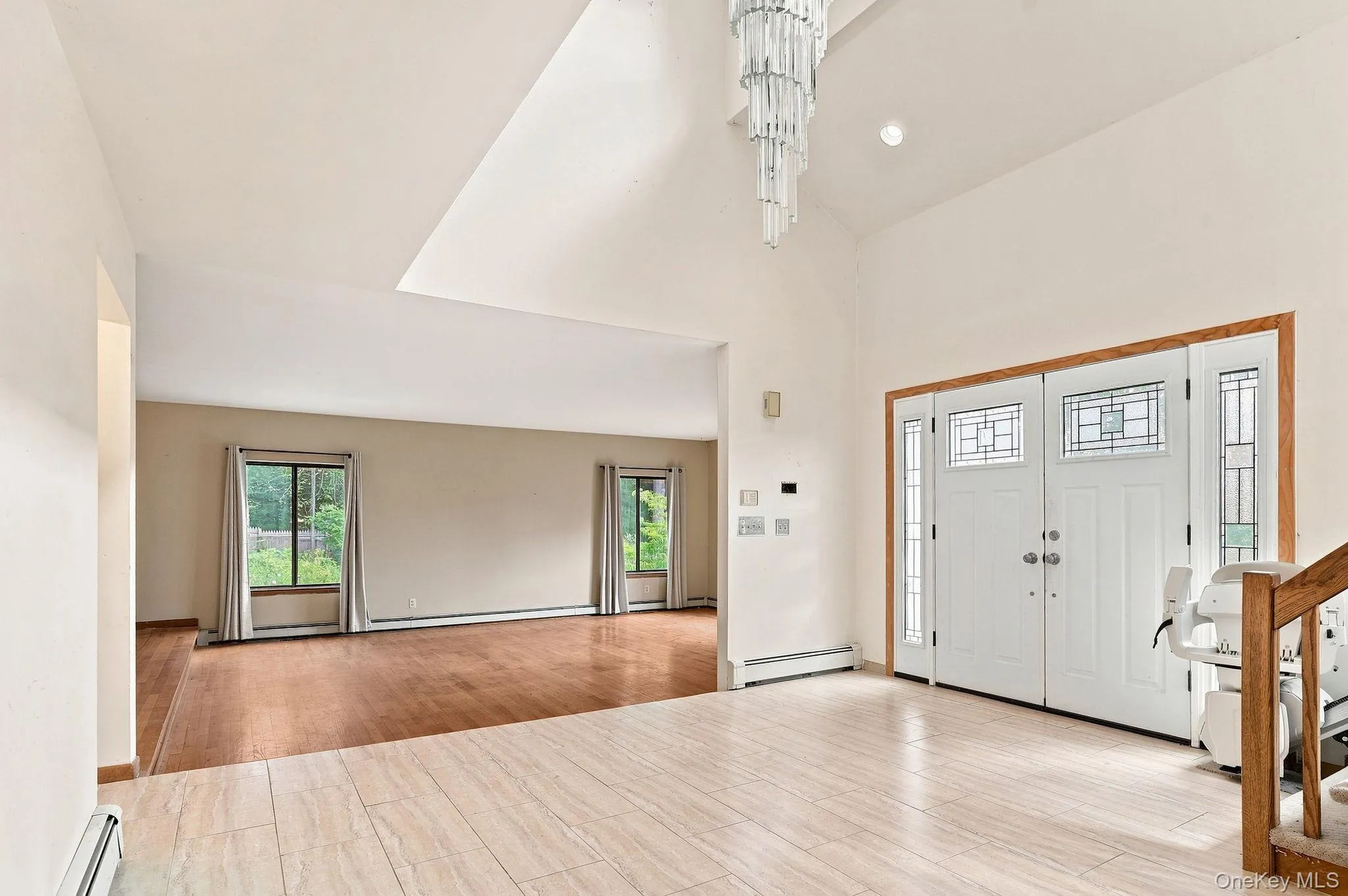 Two-story foyer with a tiered chandelier, tile flooring, and a double entry door with decorative glass panels Two-story foyer with a tiered chandelier, tile flooring, and a double entry door with decorative glass panels