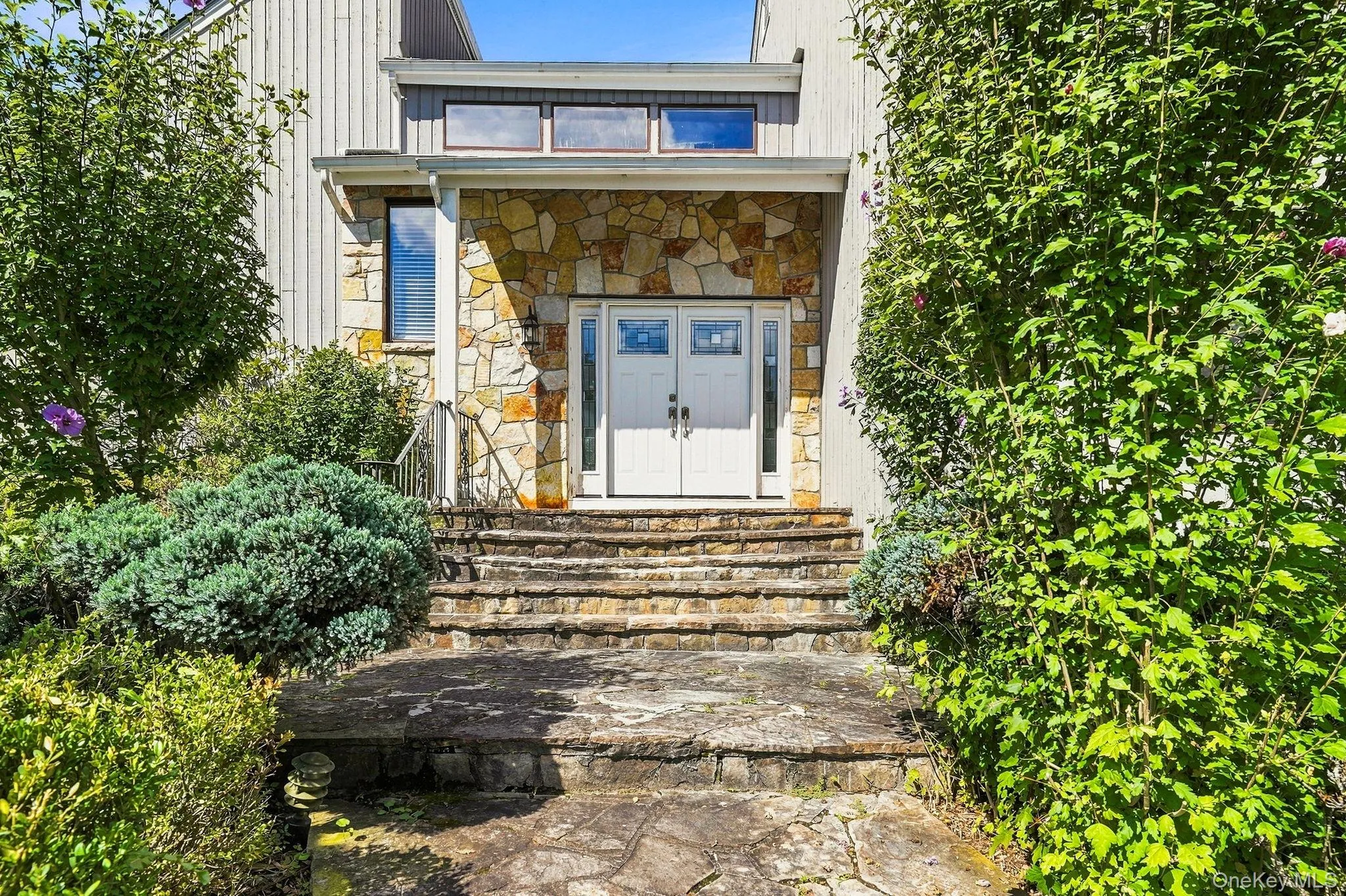 Stone entryway with a double door, transom windows, and a stone-clad facade Stone entryway with a double door, transom windows, and a stone-clad facade