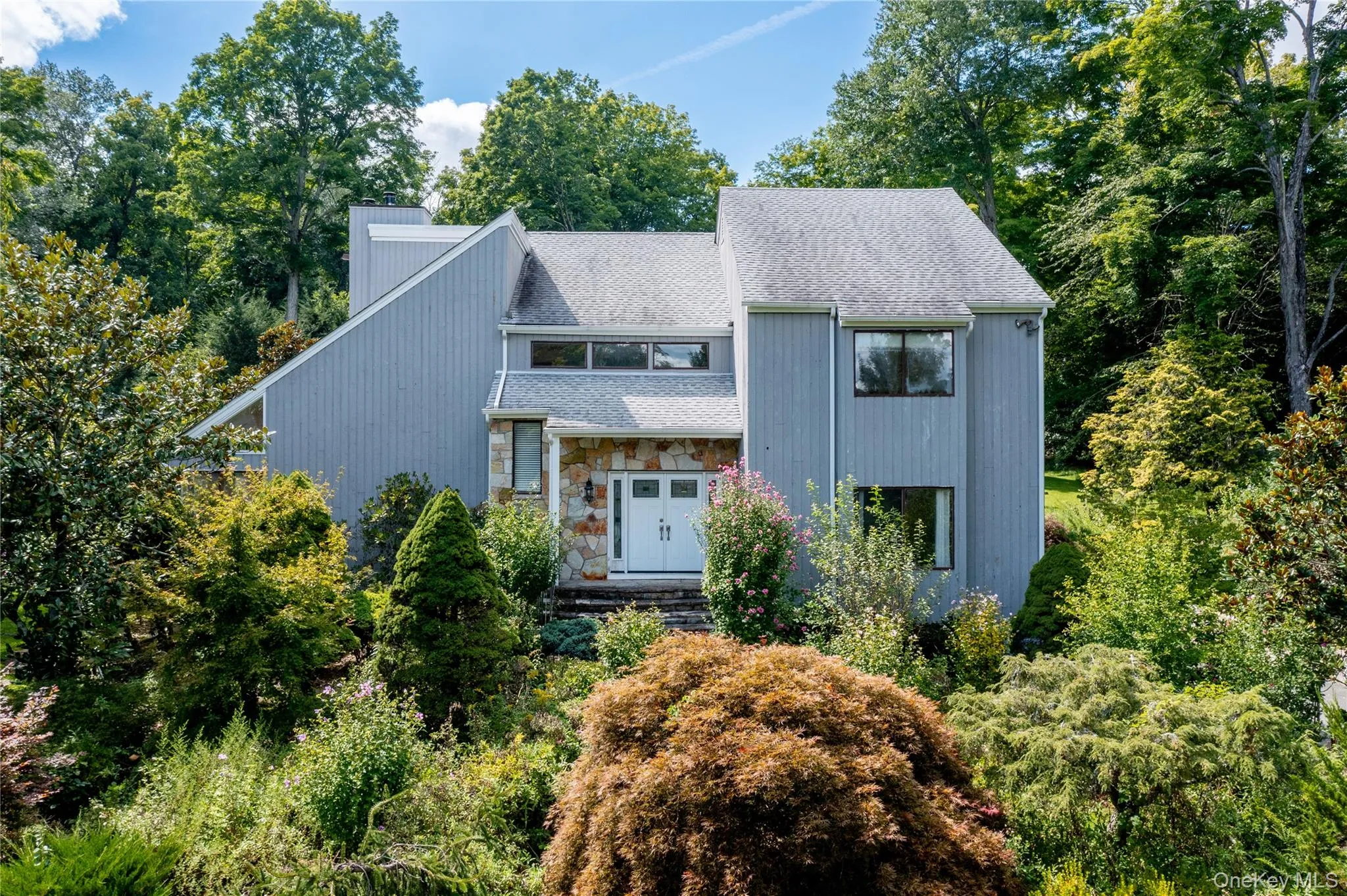 Multi-level residence featuring a gray facade and natural stone accents Multi-level residence featuring a gray facade and natural stone accents