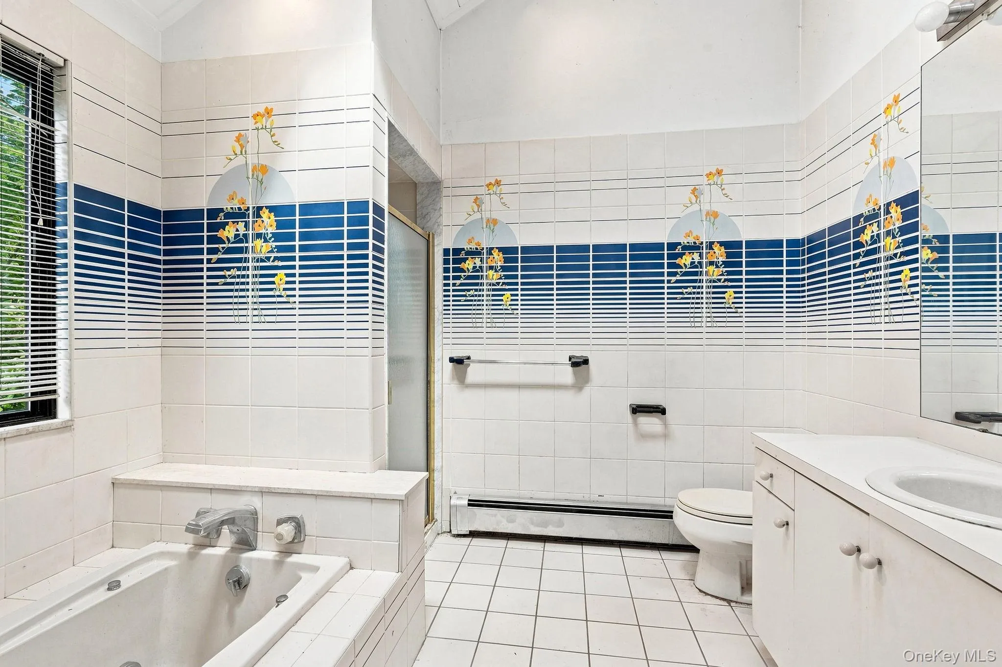 Tiled bathroom featuring a built-in tub, separate shower enclosure, single vanity with integrated sink, and white ceramic tile flooring Tiled bathroom featuring a built-in tub, separate shower enclosure, single vanity with integrated sink, and white ceramic tile flooring