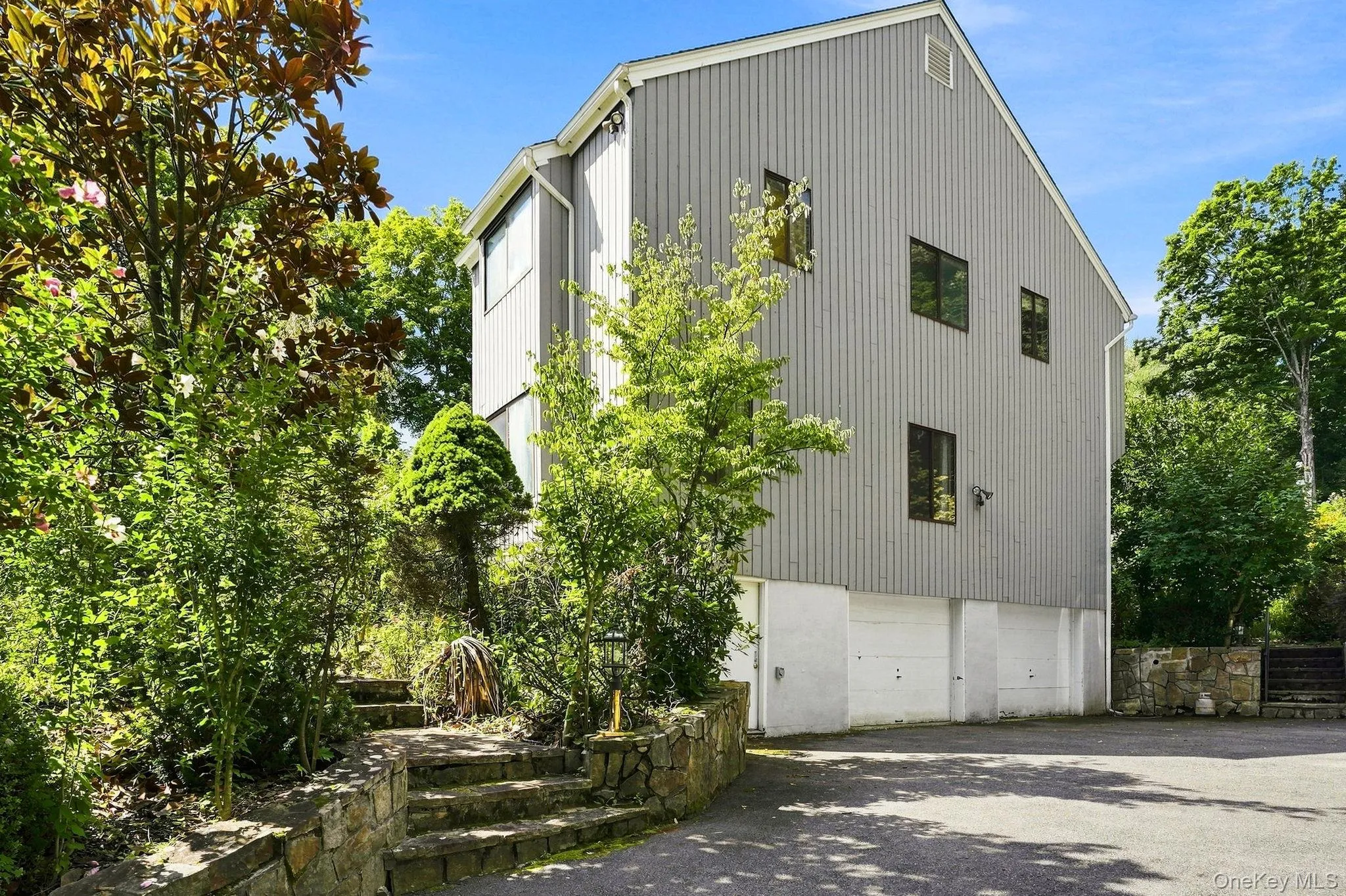 Vertical siding exterior, multiple garage bays, stone retaining wall, stone steps, and mature landscaping Vertical siding exterior, multiple garage bays, stone retaining wall, stone steps, and mature landscaping