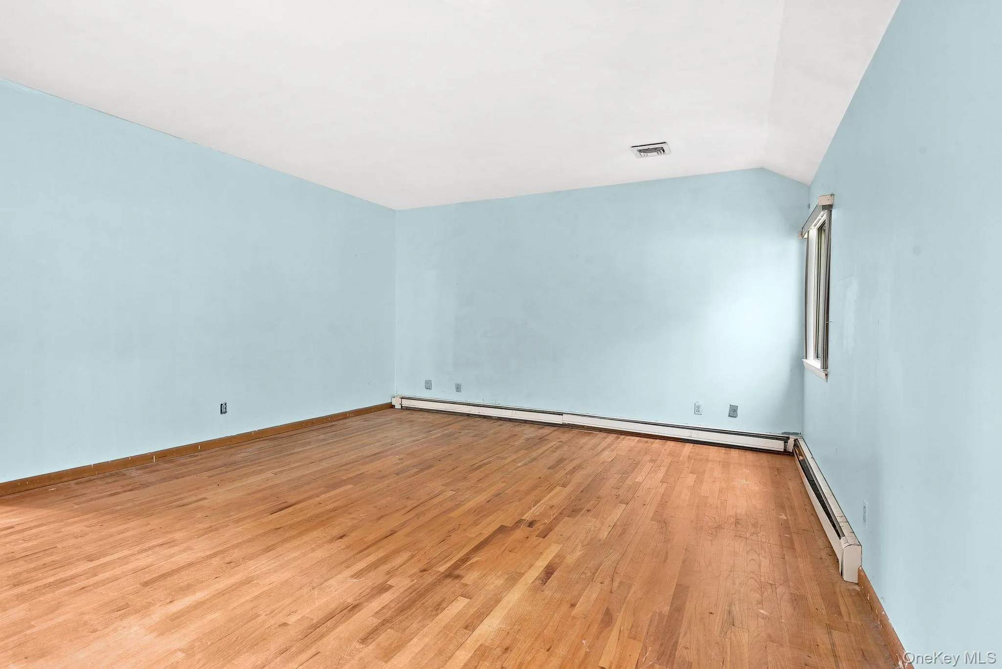 Hardwood flooring, light blue wall paint, white ceiling, window with white trim, and baseboard heating Hardwood flooring, light blue wall paint, white ceiling, window with white trim, and baseboard heating