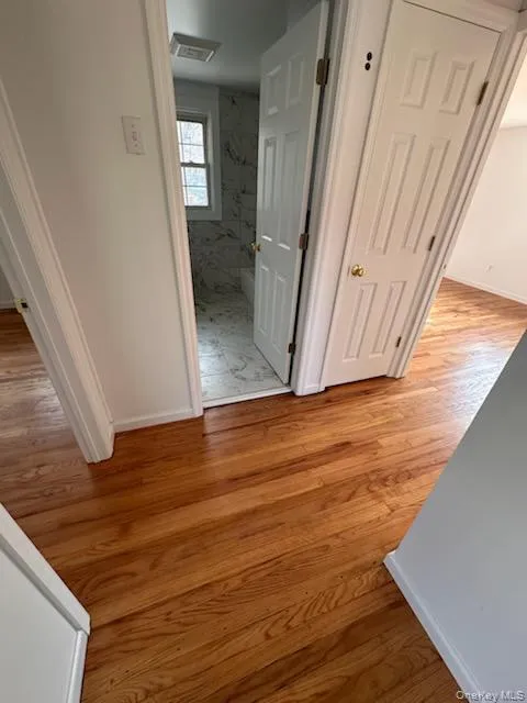 Corridor featuring light wood-style floors and baseboards Corridor featuring light wood-style floors and baseboards