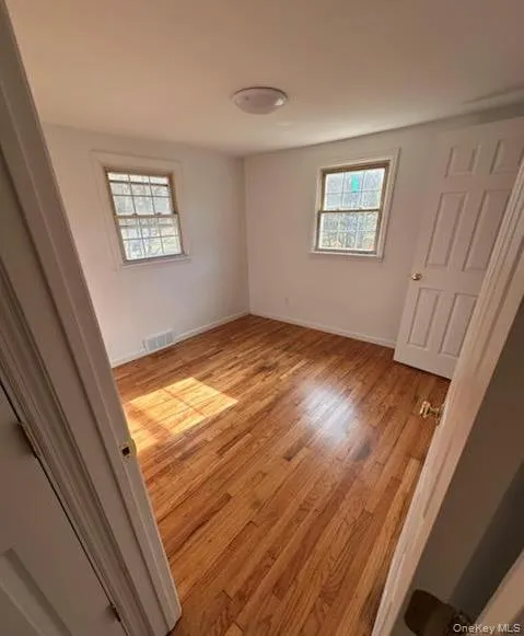 Unfurnished bedroom with light wood-style floors and multiple windows Unfurnished bedroom with light wood-style floors and multiple windows