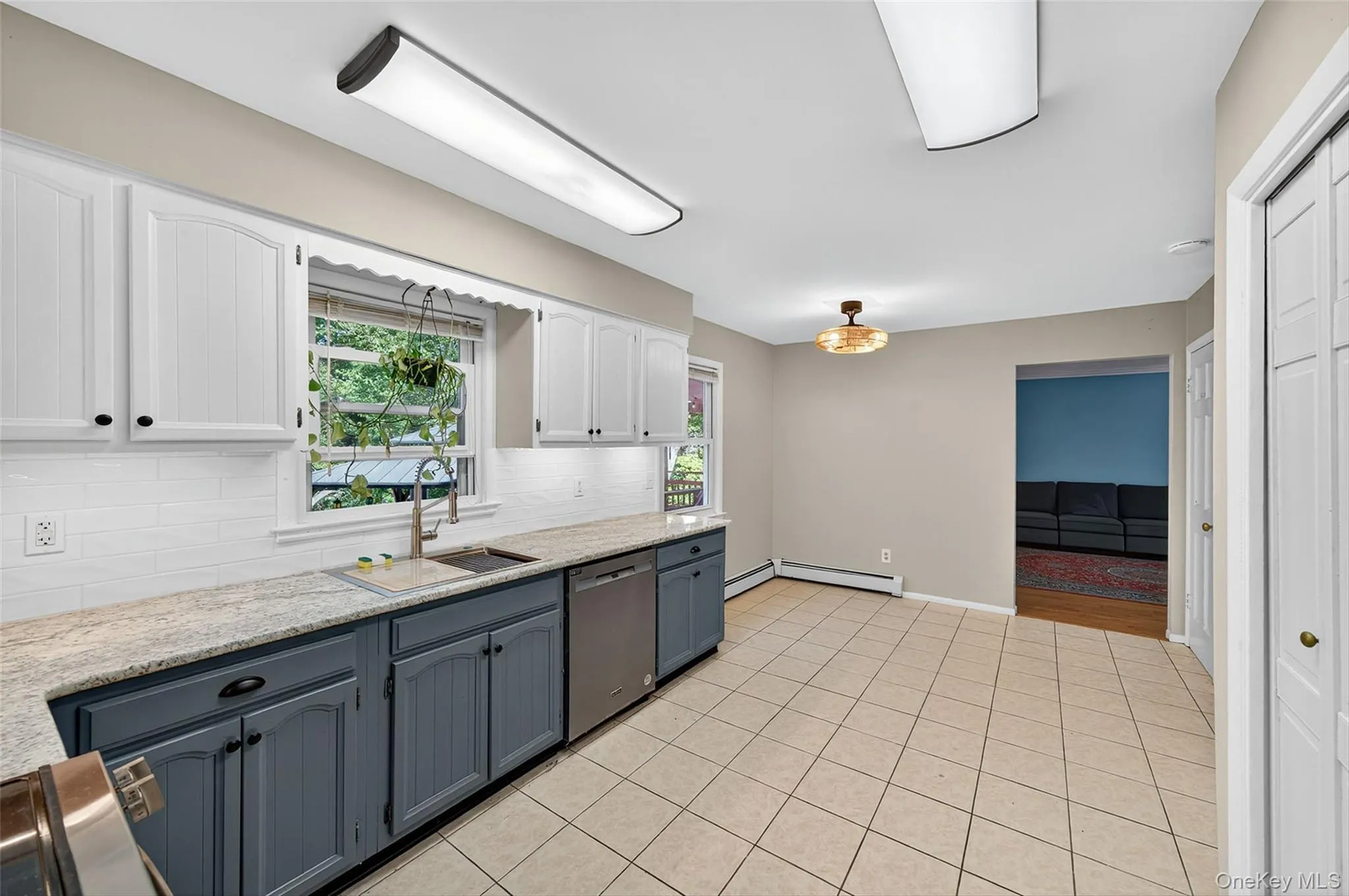 Kitchen featuring white cabinetry, light stone countertops, backsplash, and healthy amount of natural light Kitchen featuring white cabinetry, light stone countertops, backsplash, and healthy amount of natural light