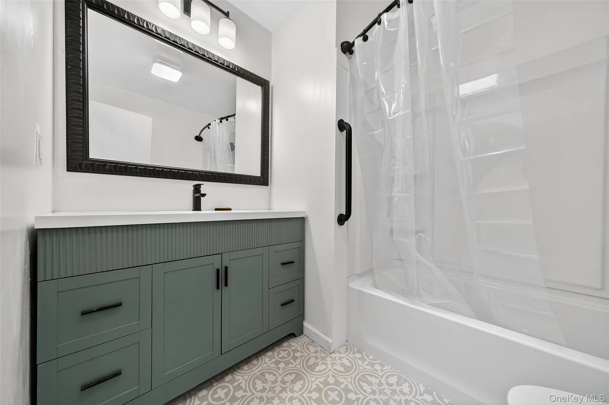 Full bathroom featuring shower / bath combo with shower curtain, vanity, and light tile patterned flooring Full bathroom featuring shower / bath combo with shower curtain, vanity, and light tile patterned flooring
