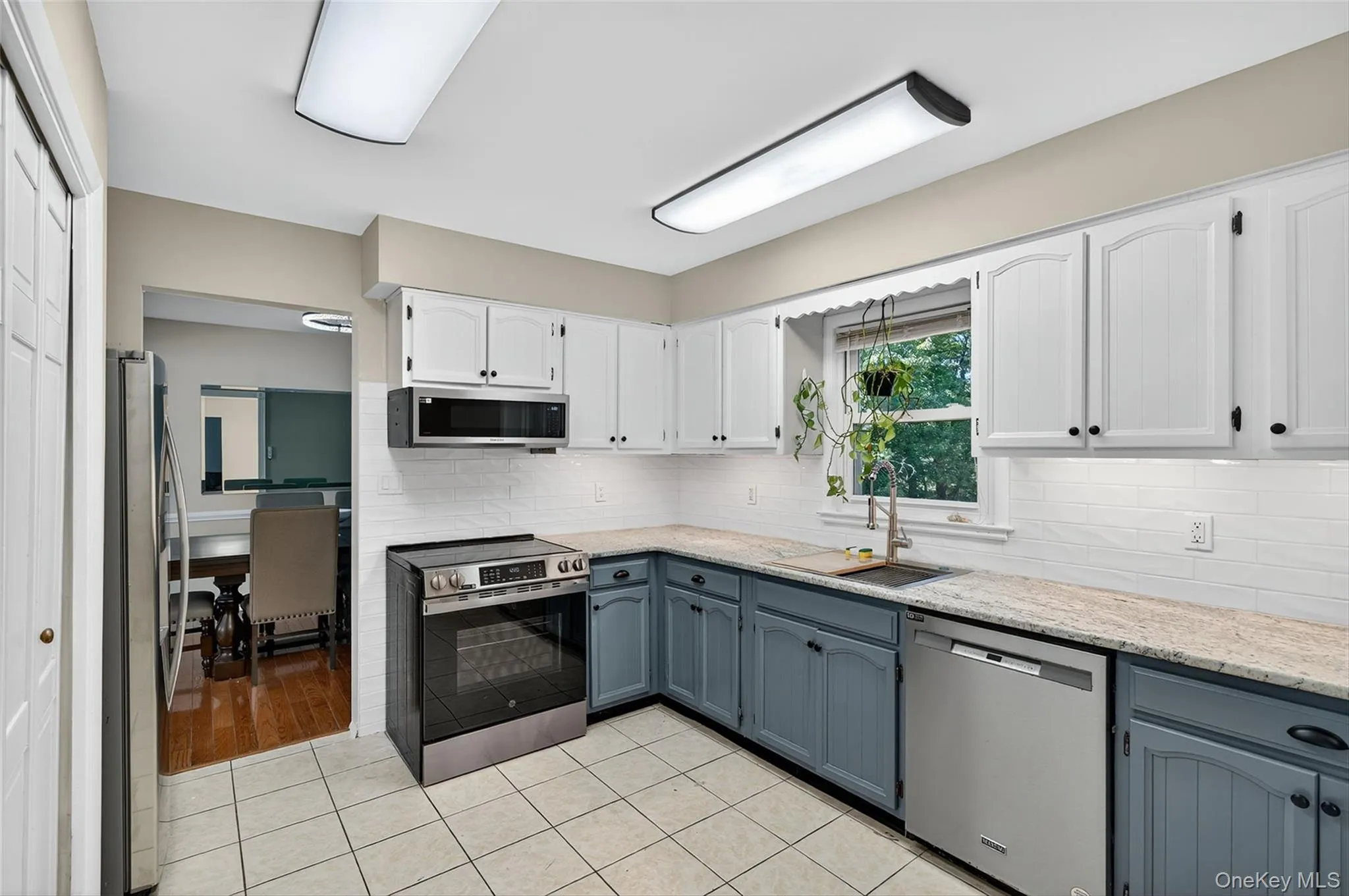 Kitchen with appliances with stainless steel finishes, white cabinetry, light stone countertops, gray cabinetry, and light tile patterned floors Kitchen with appliances with stainless steel finishes, white cabinetry, light stone countertops, gray cabinetry, and light tile patterned floors