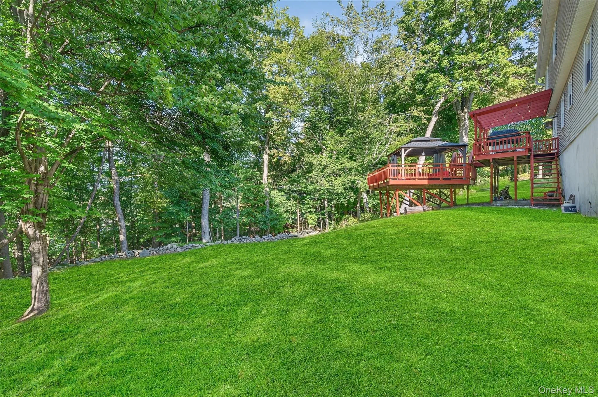 View of grassy yard with a wooden deck, a gazebo, and stairs View of grassy yard with a wooden deck, a gazebo, and stairs