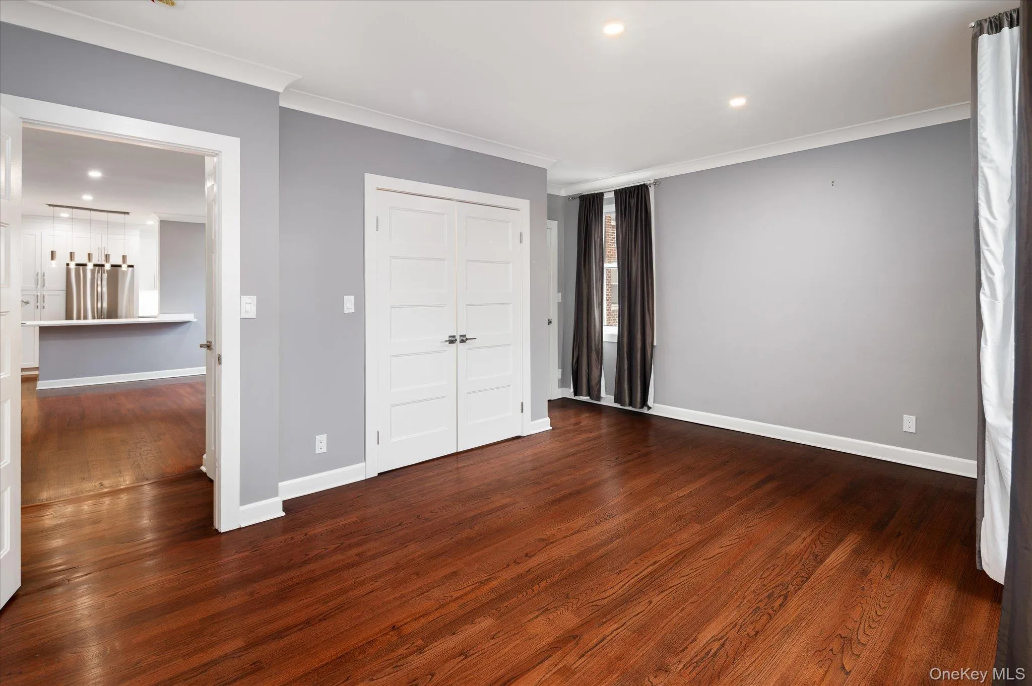 Unfurnished bedroom featuring recessed lighting, dark wood-style floors, crown molding, stainless steel fridge, and a closet Unfurnished bedroom featuring recessed lighting, dark wood-style floors, crown molding, stainless steel fridge, and a closet