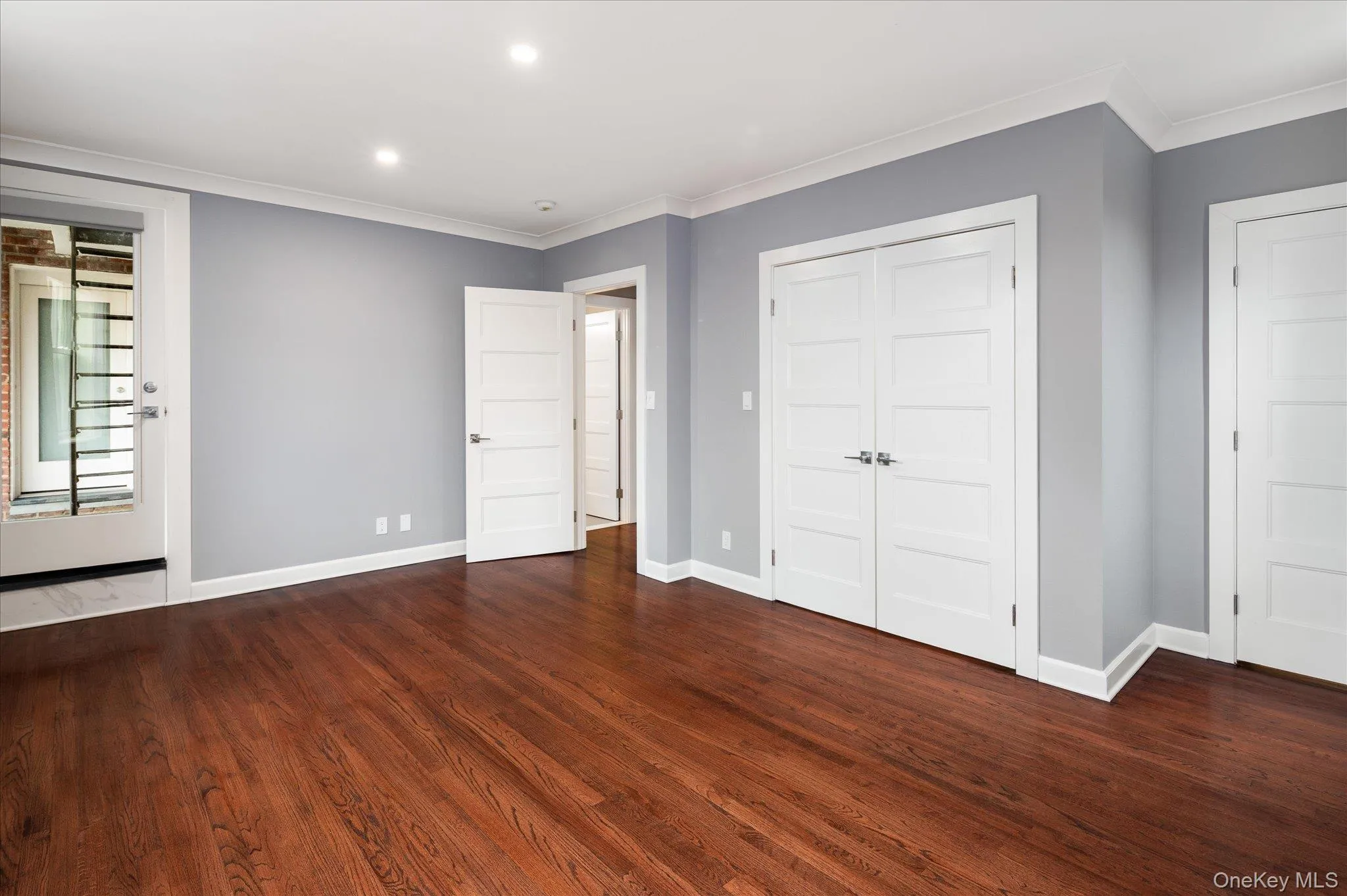 Unfurnished bedroom with ornamental molding, recessed lighting, dark wood-type flooring, and a closet Unfurnished bedroom with ornamental molding, recessed lighting, dark wood-type flooring, and a closet