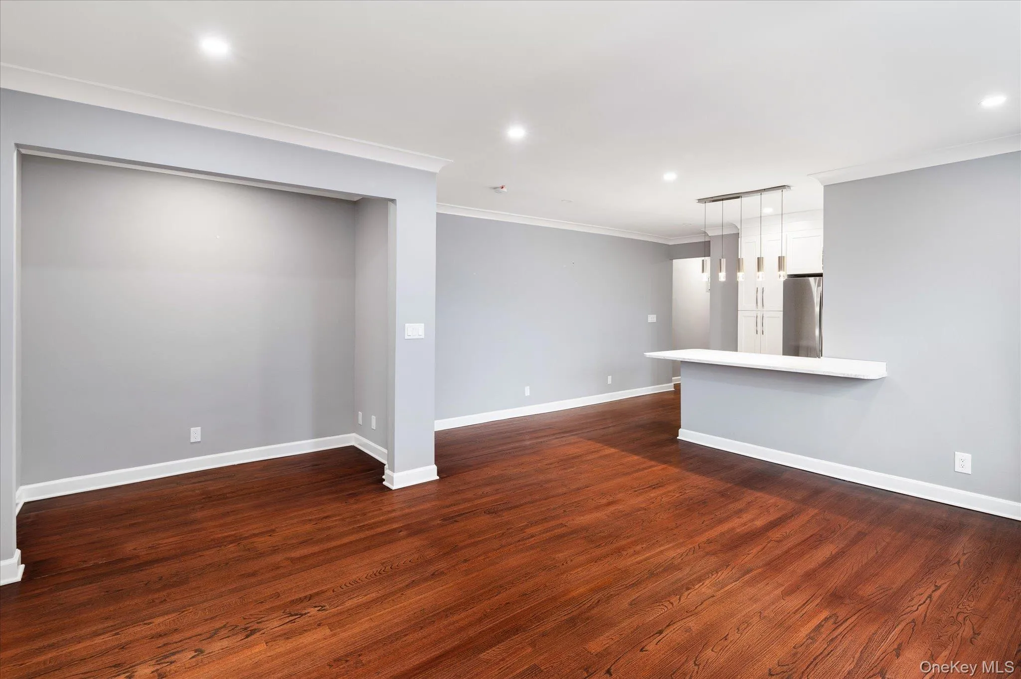 Unfurnished living room featuring crown molding, recessed lighting, and dark wood finished floors Unfurnished living room featuring crown molding, recessed lighting, and dark wood finished floors