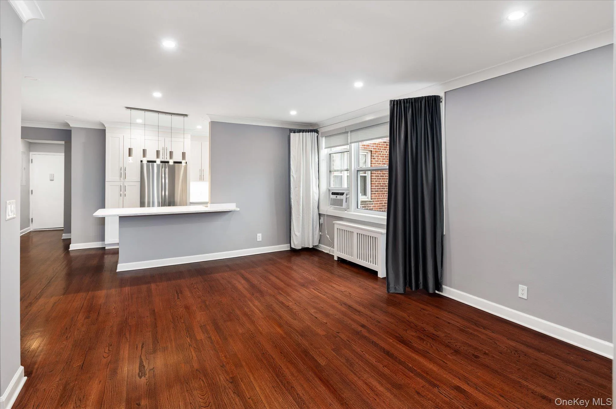 Unfurnished living room featuring ornamental molding, recessed lighting, dark wood-style floors, and radiator Unfurnished living room featuring ornamental molding, recessed lighting, dark wood-style floors, and radiator