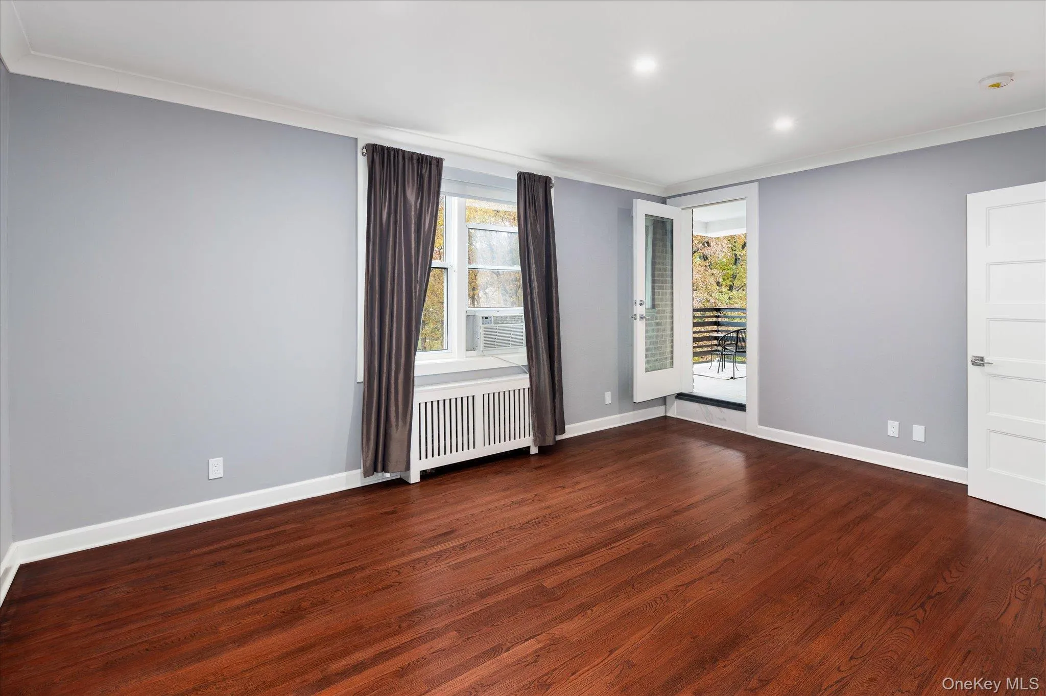 Unfurnished room with ornamental molding, dark wood finished floors, radiator heating unit, recessed lighting, and cooling unit Unfurnished room with ornamental molding, dark wood finished floors, radiator heating unit, recessed lighting, and cooling unit