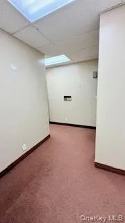 Empty room featuring a paneled ceiling and dark colored carpet Empty room featuring a paneled ceiling and dark colored carpet