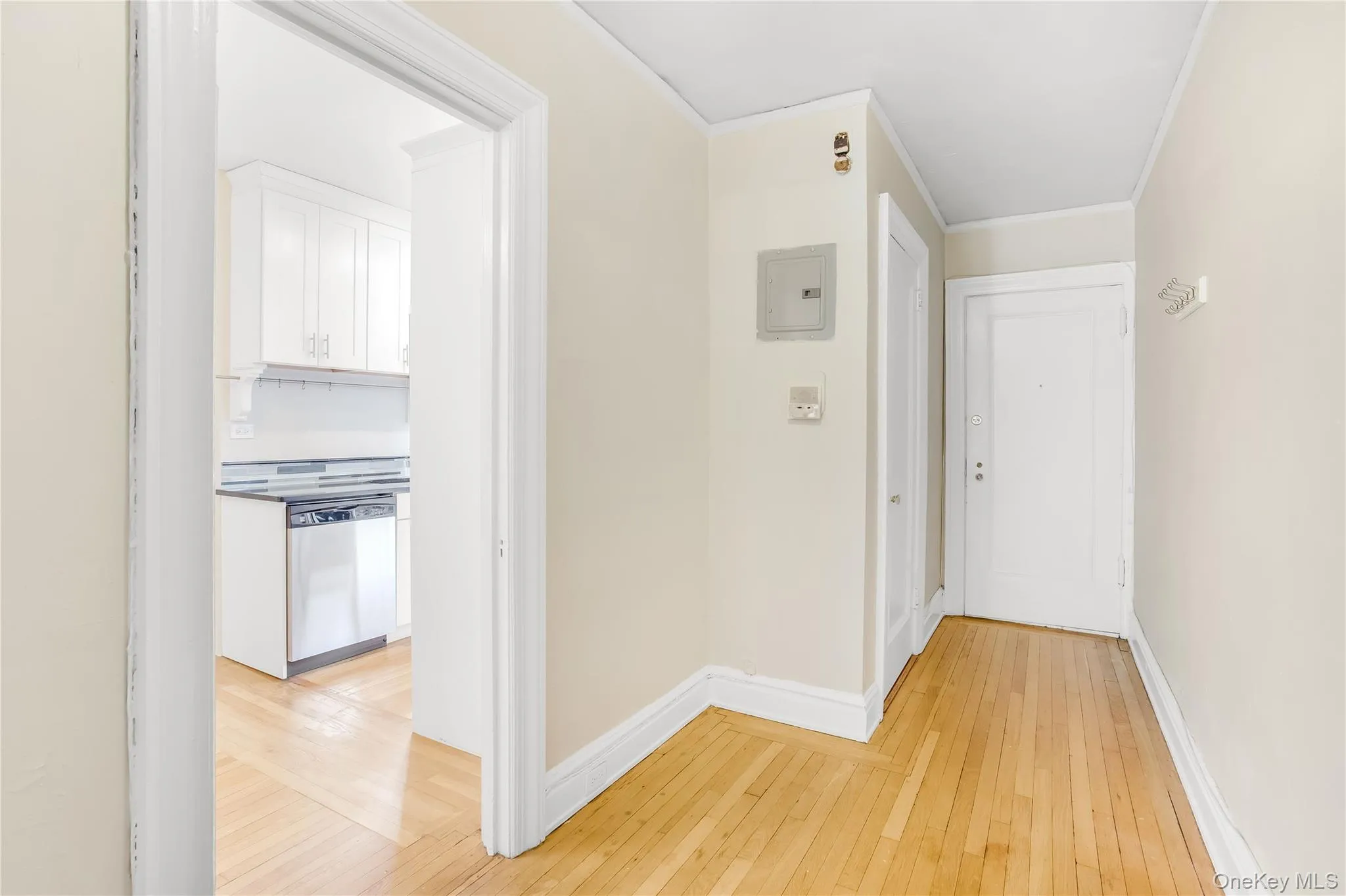 Hall with light wood-style flooring, electric panel, and ornamental molding Hall with light wood-style flooring, electric panel, and ornamental molding