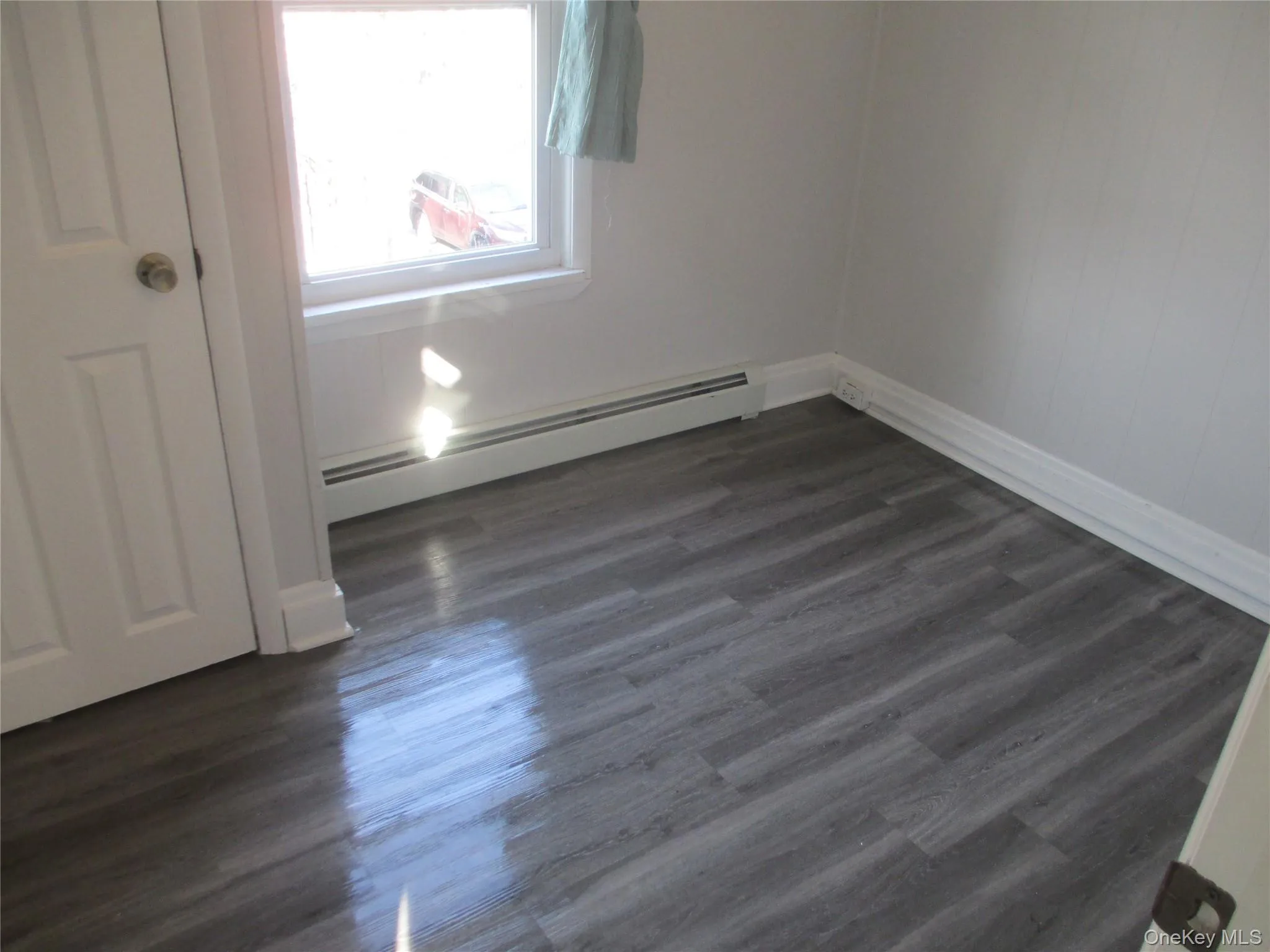 Empty room featuring baseboard heating and dark wood finished floors Empty room featuring baseboard heating and dark wood finished floors