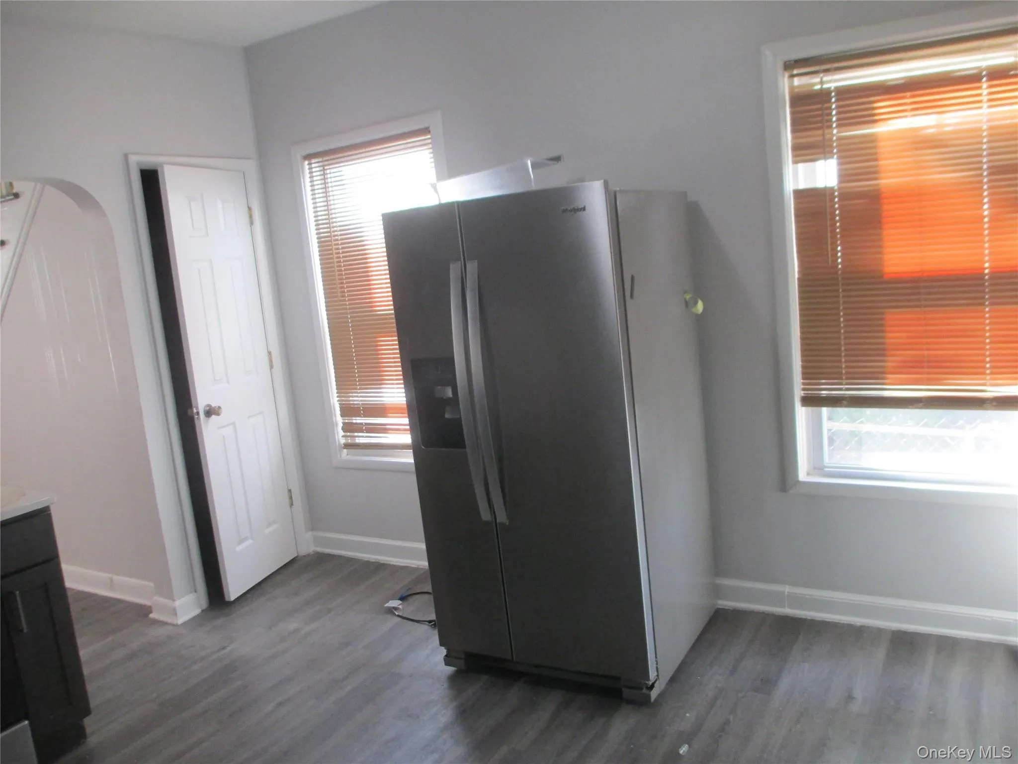 Kitchen featuring stainless steel fridge with ice dispenser, dark wood finished floors, healthy amount of natural light, and arched walkways Kitchen featuring stainless steel fridge with ice dispenser, dark wood finished floors, healthy amount of natural light, and arched walkways