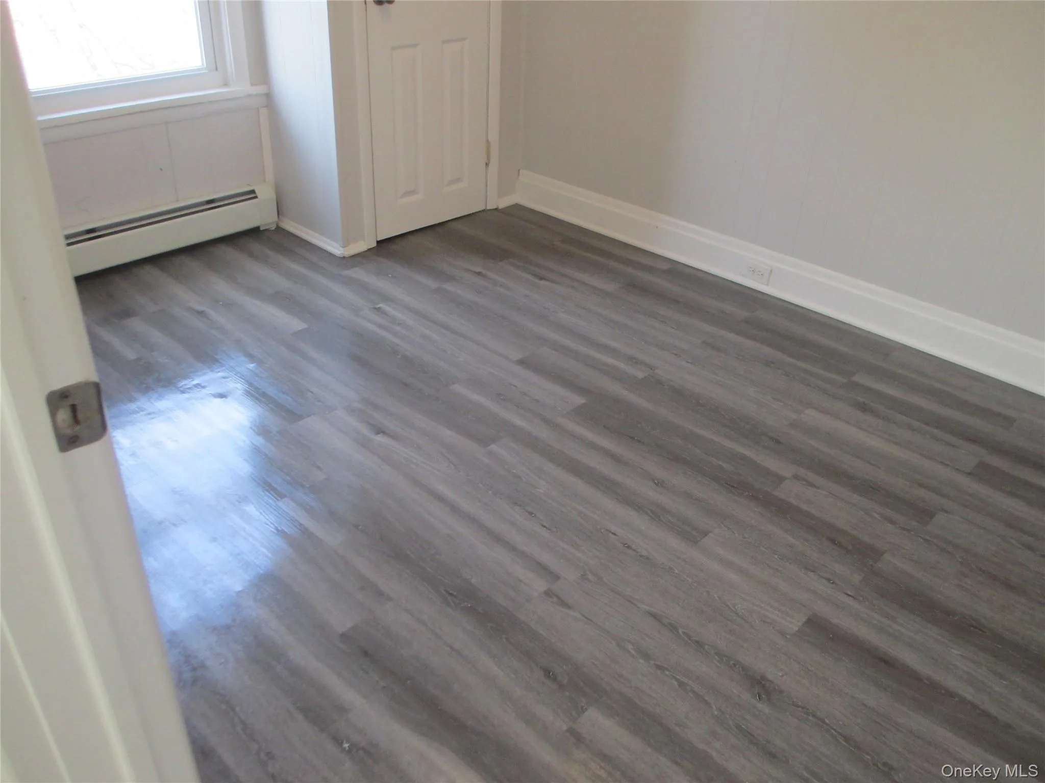 Unfurnished room with a baseboard heating unit and dark wood-style floors Unfurnished room with a baseboard heating unit and dark wood-style floors