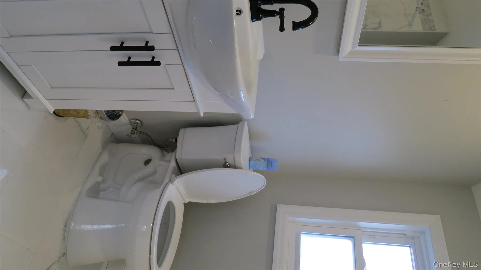 Half bathroom with vanity and light marble finish floors Half bathroom with vanity and light marble finish floors