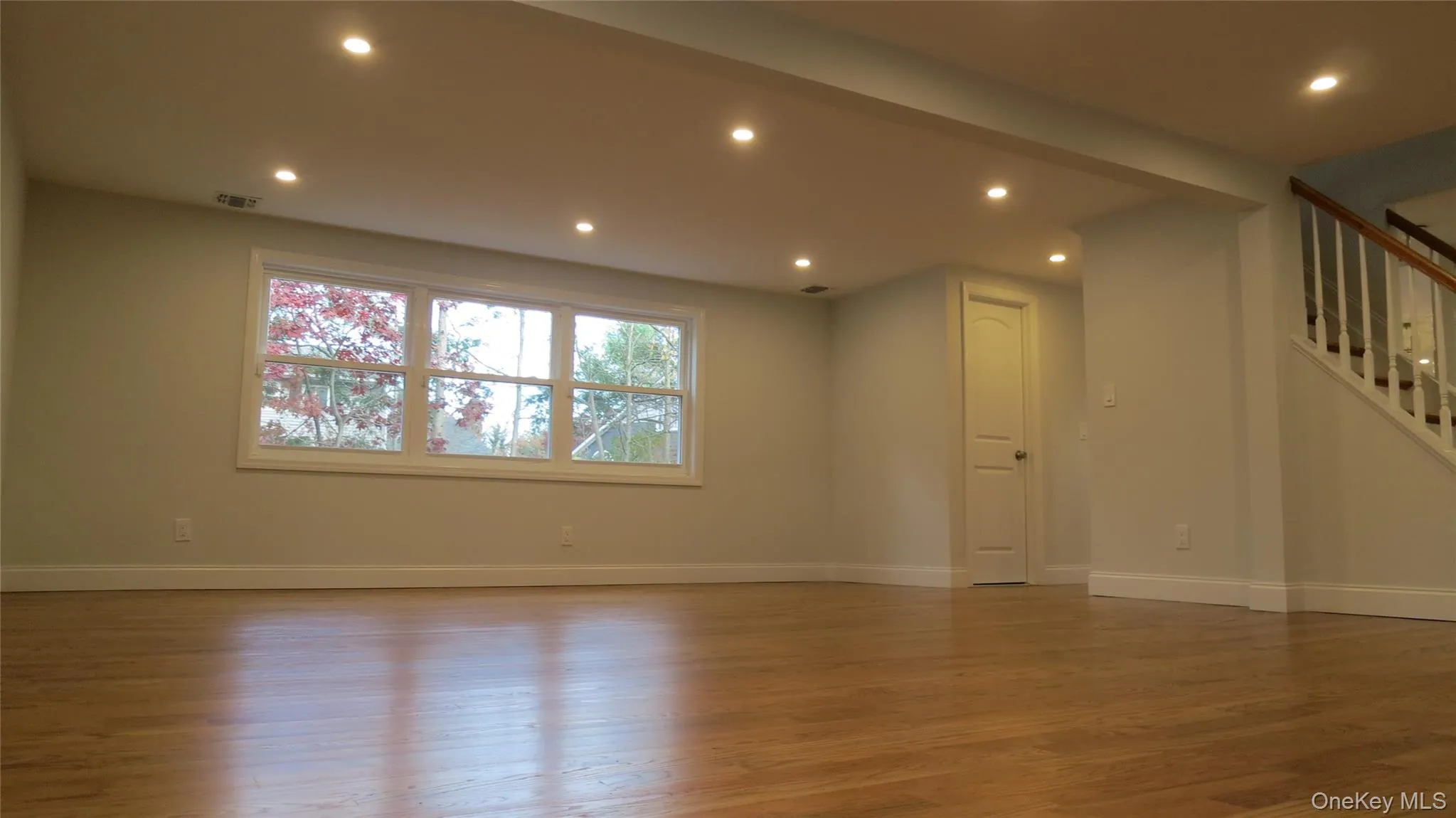 Unfurnished room with recessed lighting, light wood-style floors, and stairs Unfurnished room with recessed lighting, light wood-style floors, and stairs