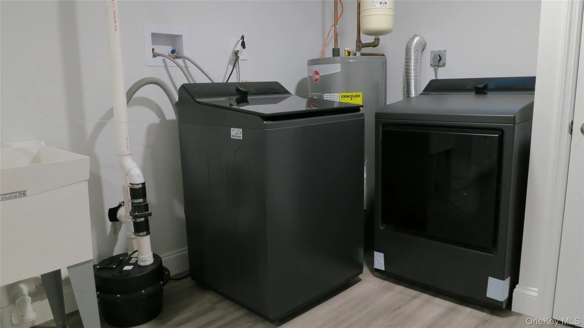 Laundry room featuring light wood-style flooring, water heater, and washing machine and dryer Laundry room featuring light wood-style flooring, water heater, and washing machine and dryer