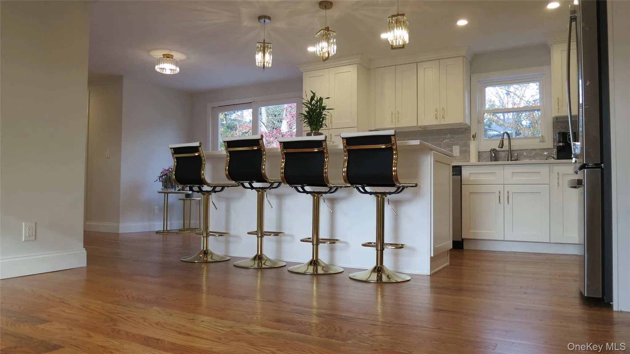 Kitchen featuring decorative light fixtures, white cabinets, plenty of natural light, light wood-style flooring, and recessed lighting Kitchen featuring decorative light fixtures, white cabinets, plenty of natural light, light wood-style flooring, and recessed lighting