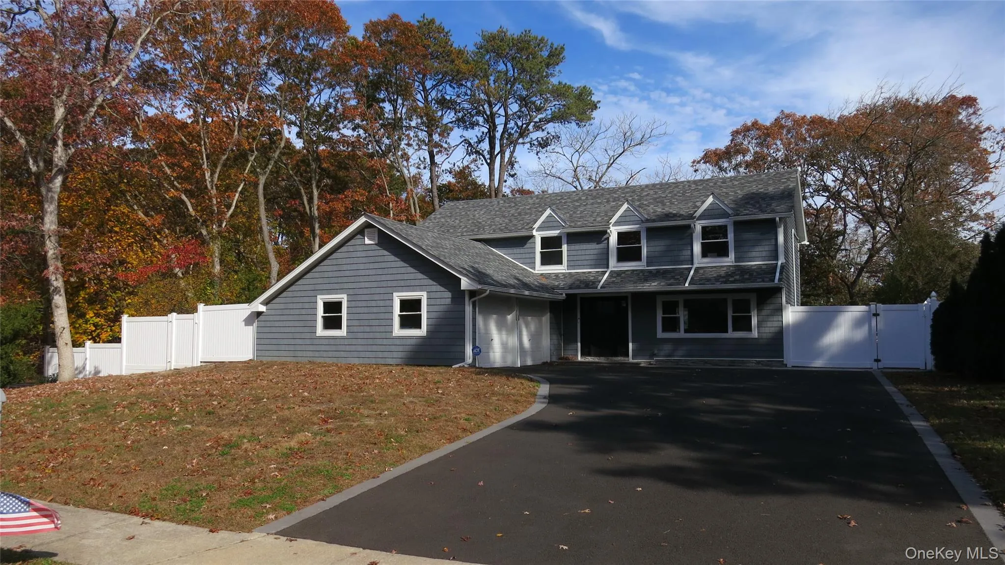 Cape cod home with a gate, asphalt driveway, a shingled roof, view of wooded area, and a garage Cape cod home with a gate, asphalt driveway, a shingled roof, view of wooded area, and a garage