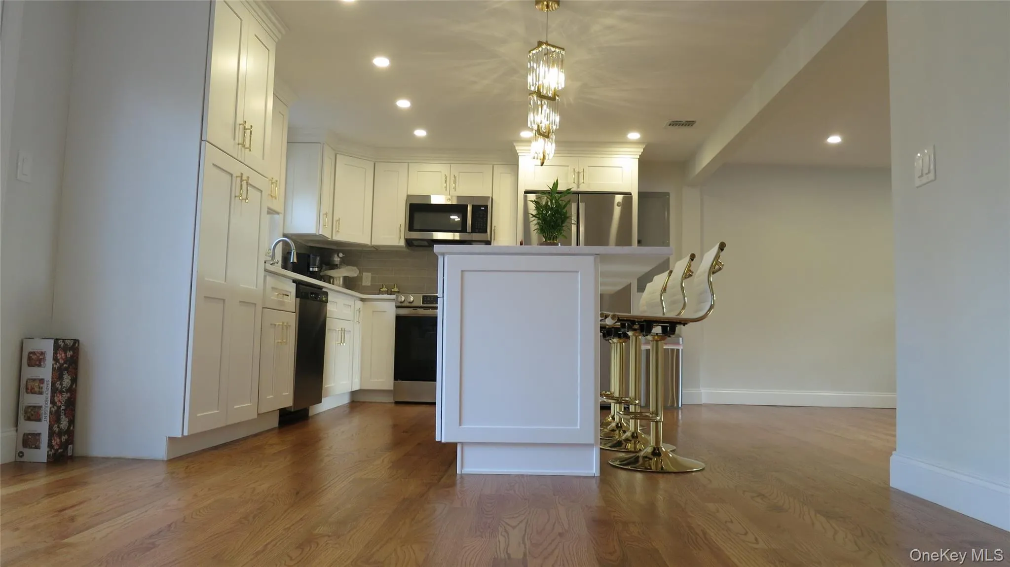 Kitchen featuring a breakfast bar area, appliances with stainless steel finishes, a kitchen island, white cabinets, and recessed lighting Kitchen featuring a breakfast bar area, appliances with stainless steel finishes, a kitchen island, white cabinets, and recessed lighting