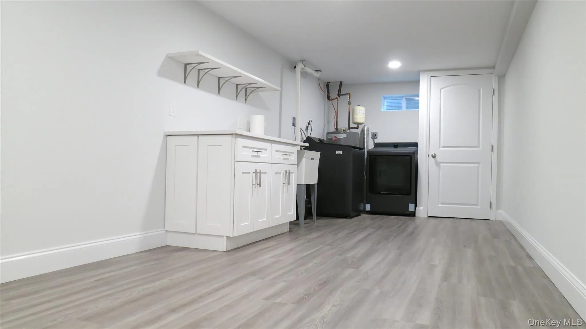Laundry area with light wood-style floors, cabinet space, and electric dryer hookup Laundry area with light wood-style floors, cabinet space, and electric dryer hookup