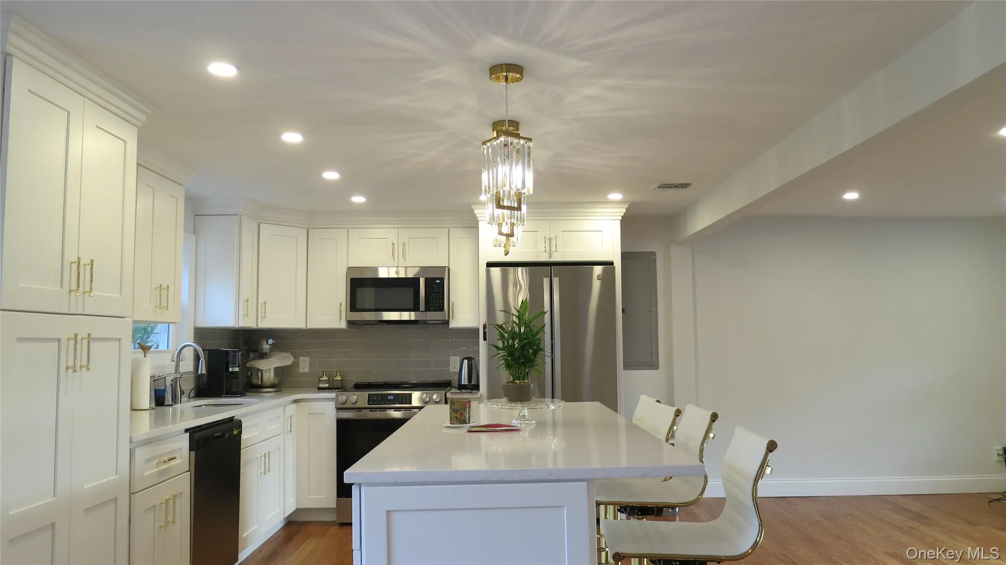 Kitchen with a kitchen bar, appliances with stainless steel finishes, light wood-style floors, backsplash, and recessed lighting Kitchen with a kitchen bar, appliances with stainless steel finishes, light wood-style floors, backsplash, and recessed lighting