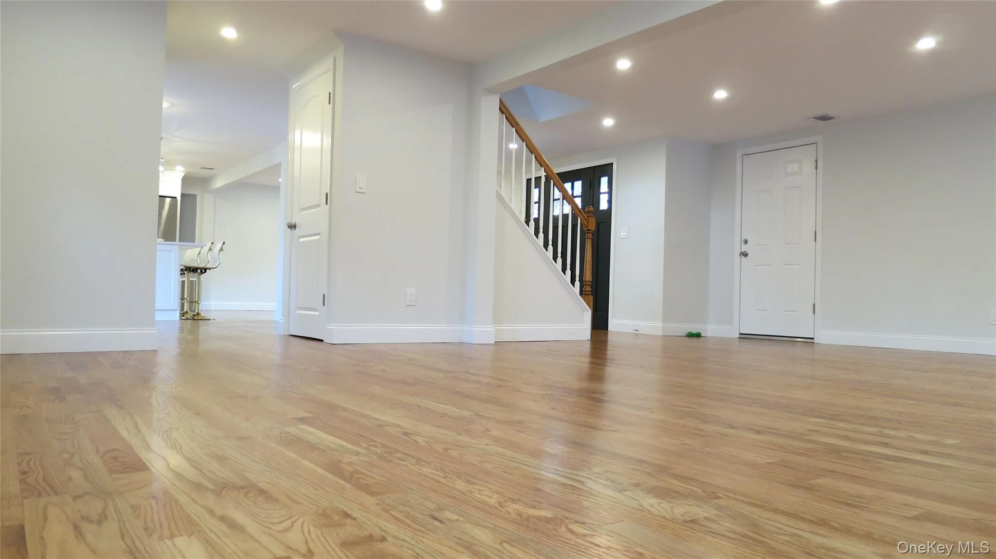 Unfurnished living room with stairway, light wood-type flooring, and recessed lighting Unfurnished living room with stairway, light wood-type flooring, and recessed lighting