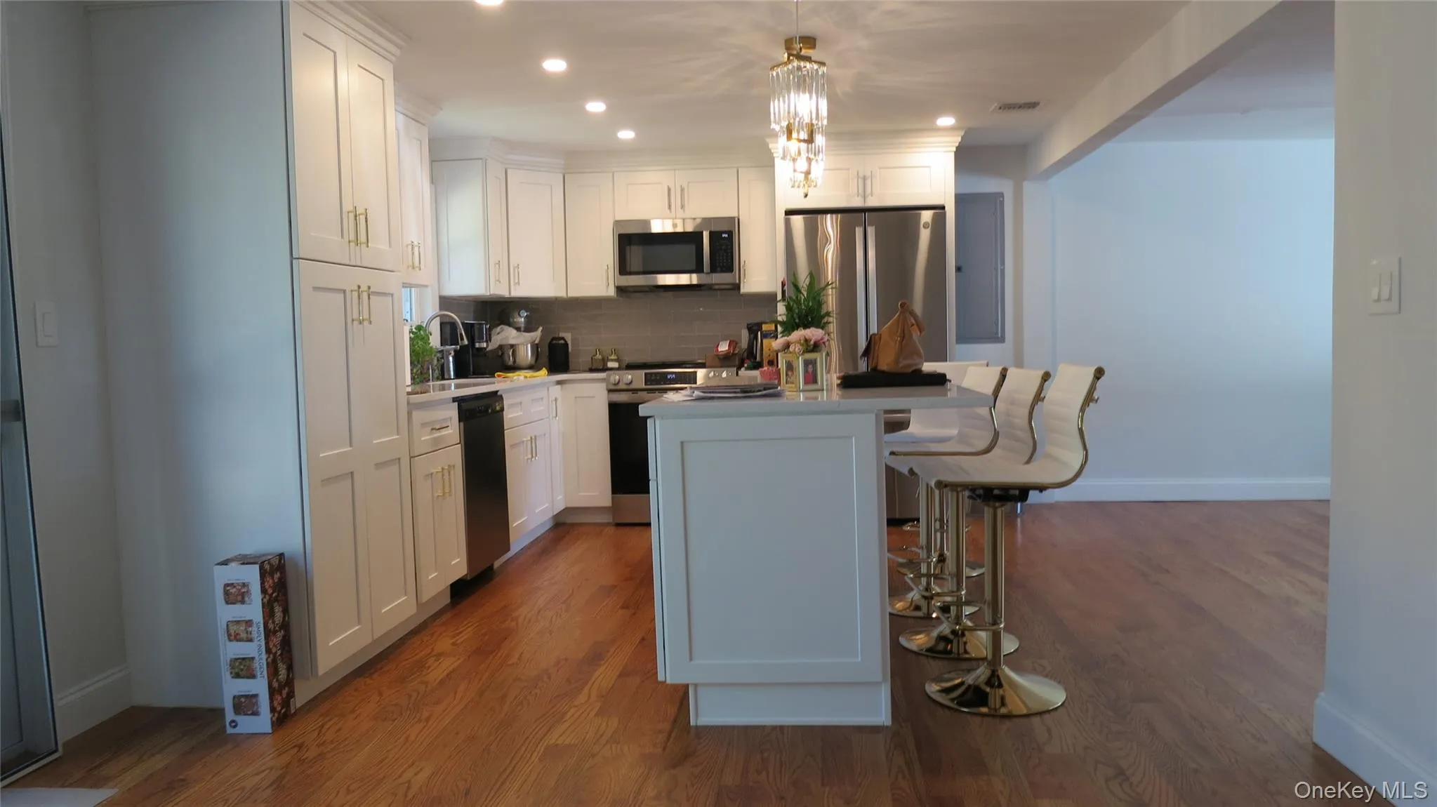 Kitchen featuring a breakfast bar area, white cabinetry, a kitchen island, decorative backsplash, and appliances with stainless steel finishes Kitchen featuring a breakfast bar area, white cabinetry, a kitchen island, decorative backsplash, and appliances with stainless steel finishes