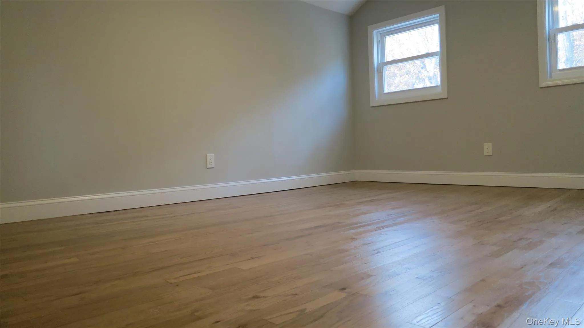Empty room featuring light wood finished floors and lofted ceiling Empty room featuring light wood finished floors and lofted ceiling