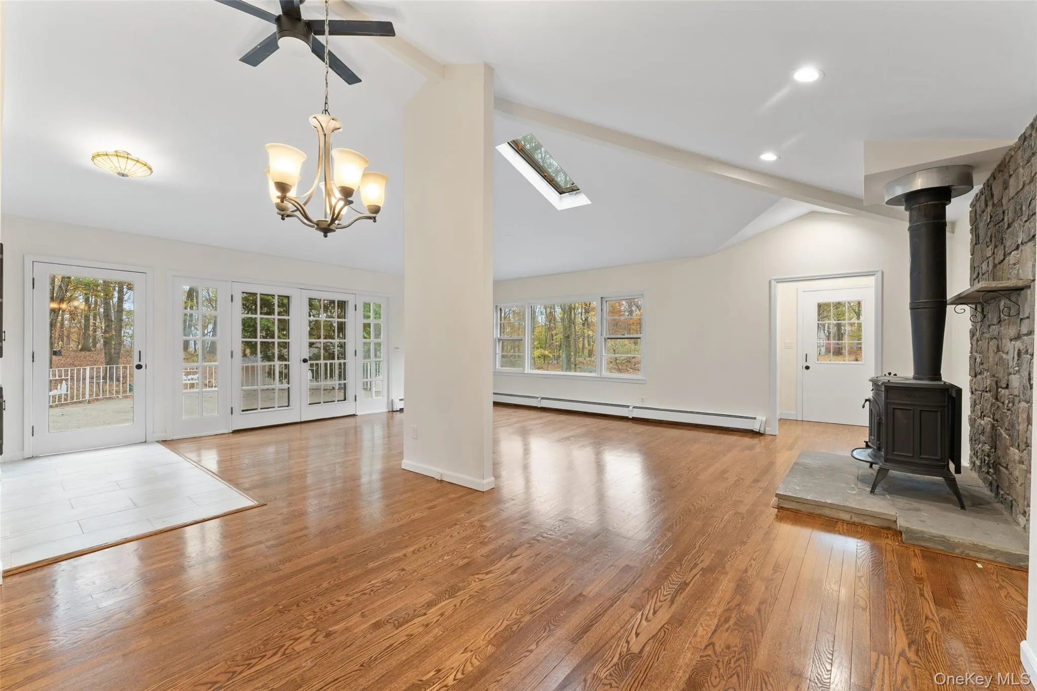 54 De Liso: Unfurnished living room featuring light wood finished floors, a wood stove, plenty of natural light, a baseboard radiator, and high vaulted ceiling 54 De Liso: Unfurnished living room featuring light wood finished floors, a wood stove, plenty of natural light, a baseboard radiator, and high vaulted ceiling