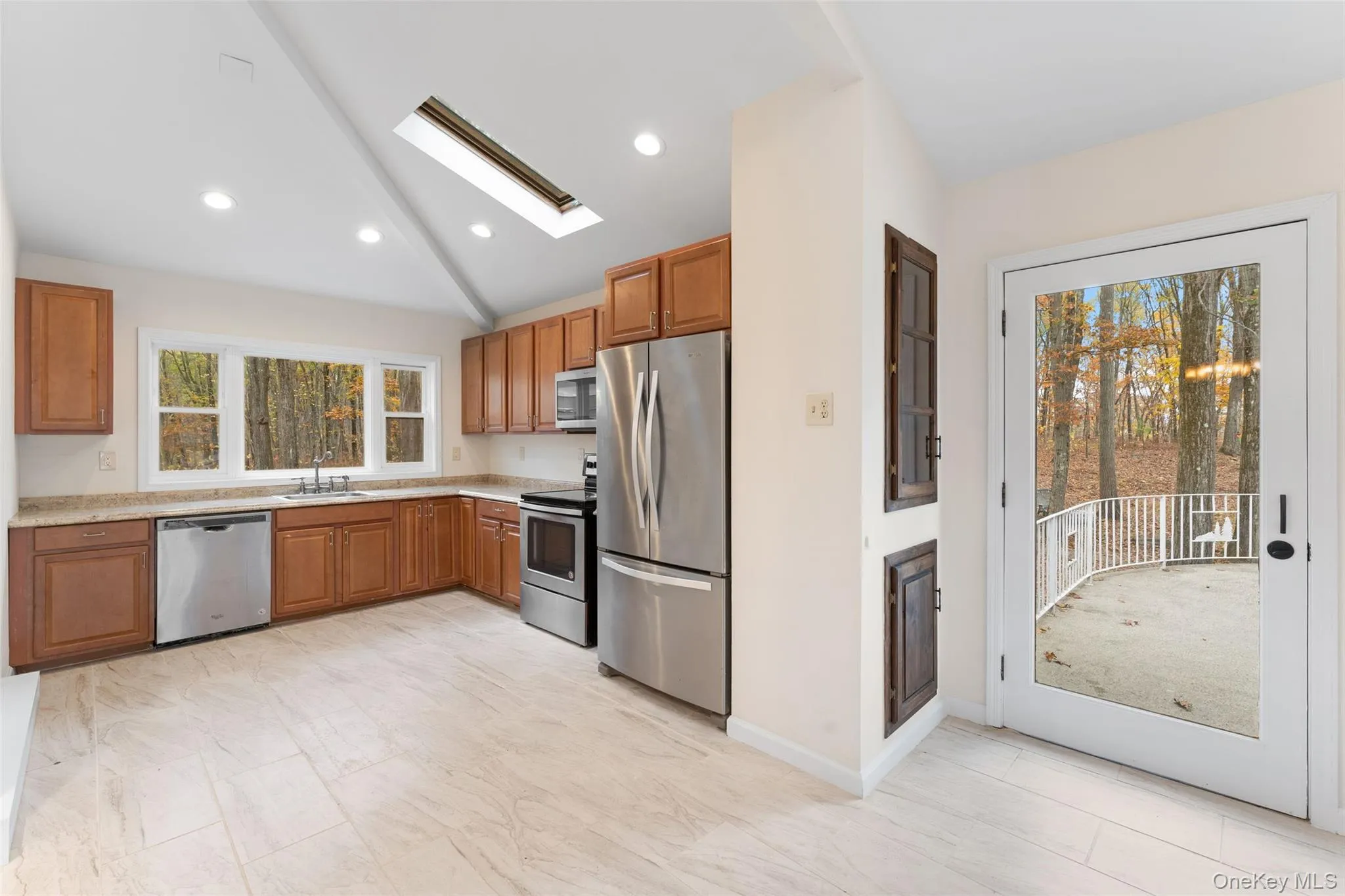 54 De Liso: Kitchen with lofted ceiling, brown cabinetry, a skylight, stainless steel appliances, and recessed lighting 54 De Liso: Kitchen with lofted ceiling, brown cabinetry, a skylight, stainless steel appliances, and recessed lighting