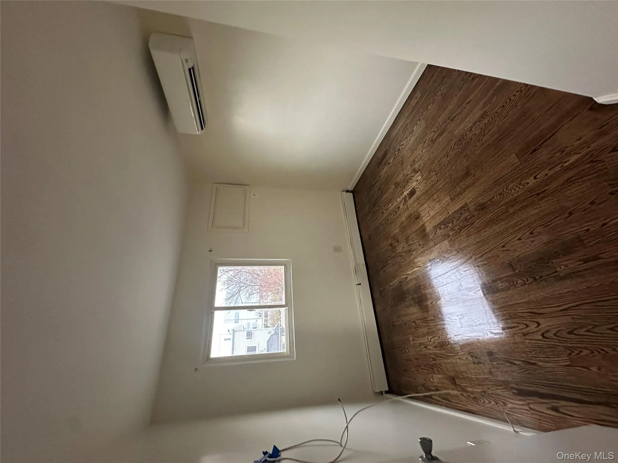 Spare room with dark wood finished floors, a baseboard heating unit, and a wall unit AC Spare room with dark wood finished floors, a baseboard heating unit, and a wall unit AC