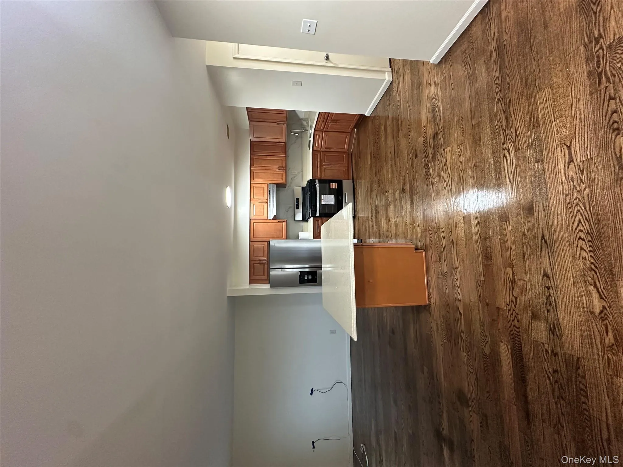 Kitchen featuring brown cabinetry, range, stainless steel fridge, and dark wood-style floors Kitchen featuring brown cabinetry, range, stainless steel fridge, and dark wood-style floors