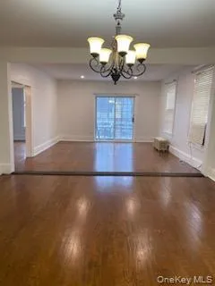 Unfurnished dining area featuring dark wood-style flooring and a chandelier Unfurnished dining area featuring dark wood-style flooring and a chandelier