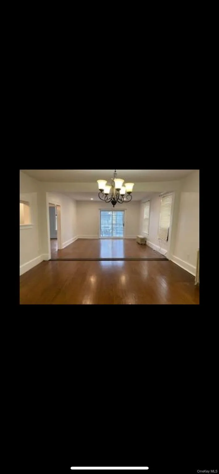 Empty room featuring wood finished floors and a chandelier Empty room featuring wood finished floors and a chandelier