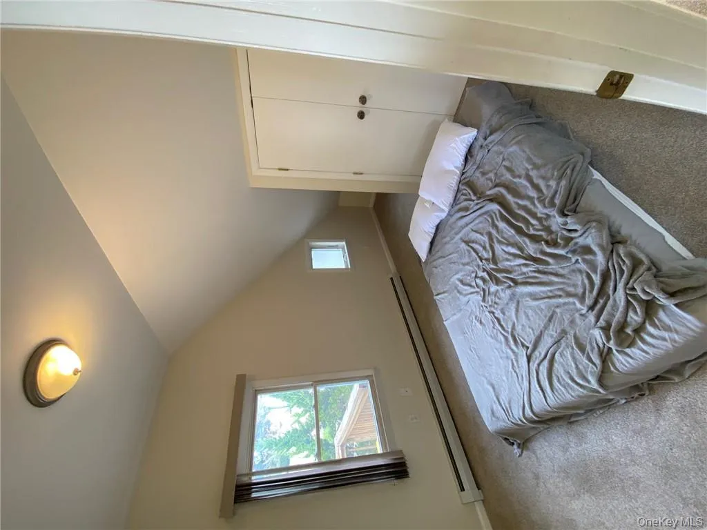 Carpeted bedroom with baseboard heating, a closet, and lofted ceiling Carpeted bedroom with baseboard heating, a closet, and lofted ceiling