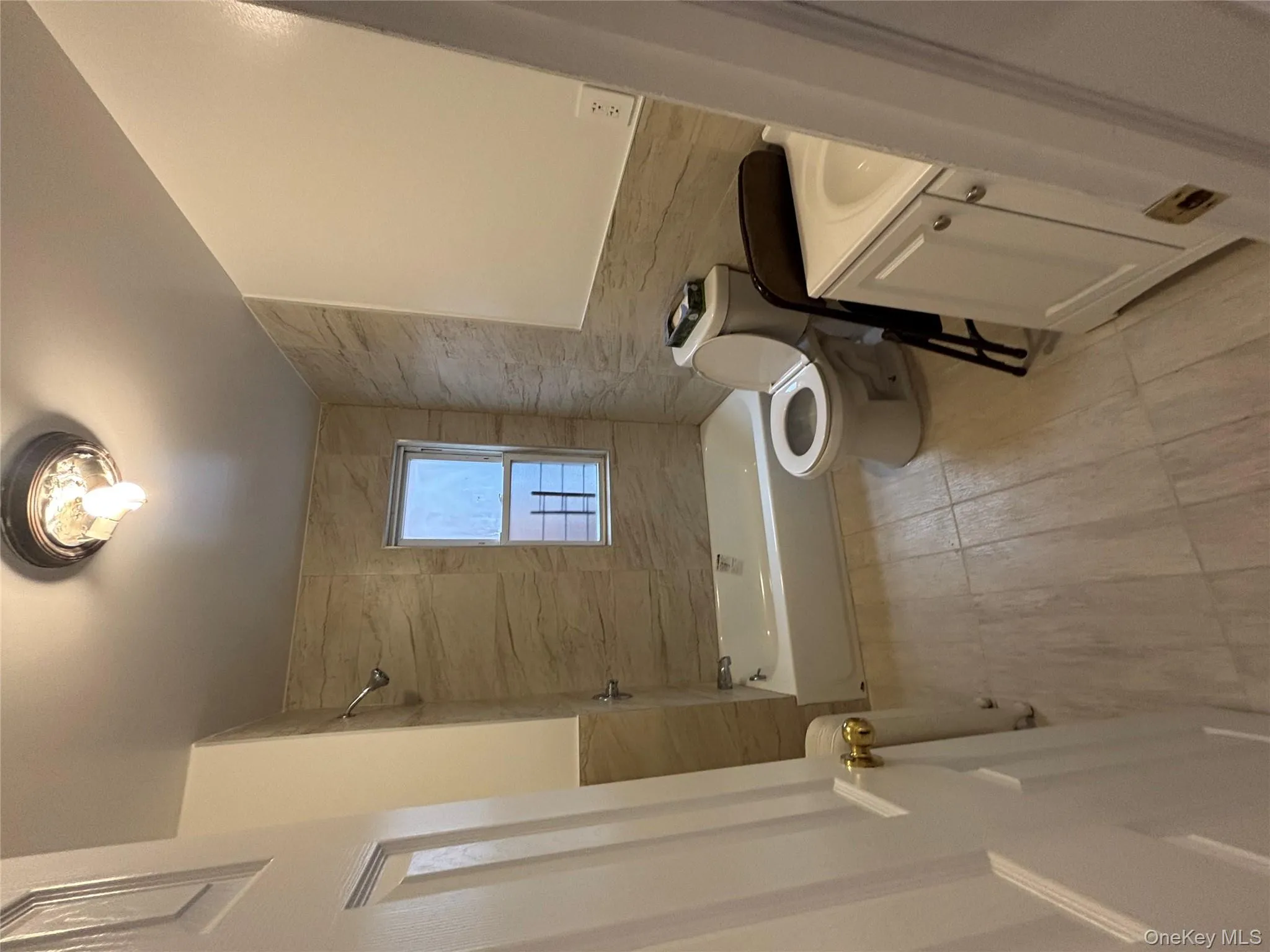 Full bath featuring vanity, tile walls, washtub / shower combination, radiator, and light wood-style floors Full bath featuring vanity, tile walls, washtub / shower combination, radiator, and light wood-style floors