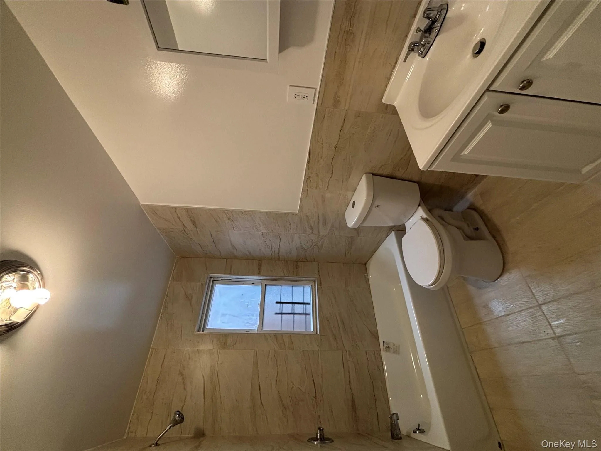 Full bathroom with tile walls, vanity, bathing tub / shower combination, and light wood-style floors Full bathroom with tile walls, vanity, bathing tub / shower combination, and light wood-style floors