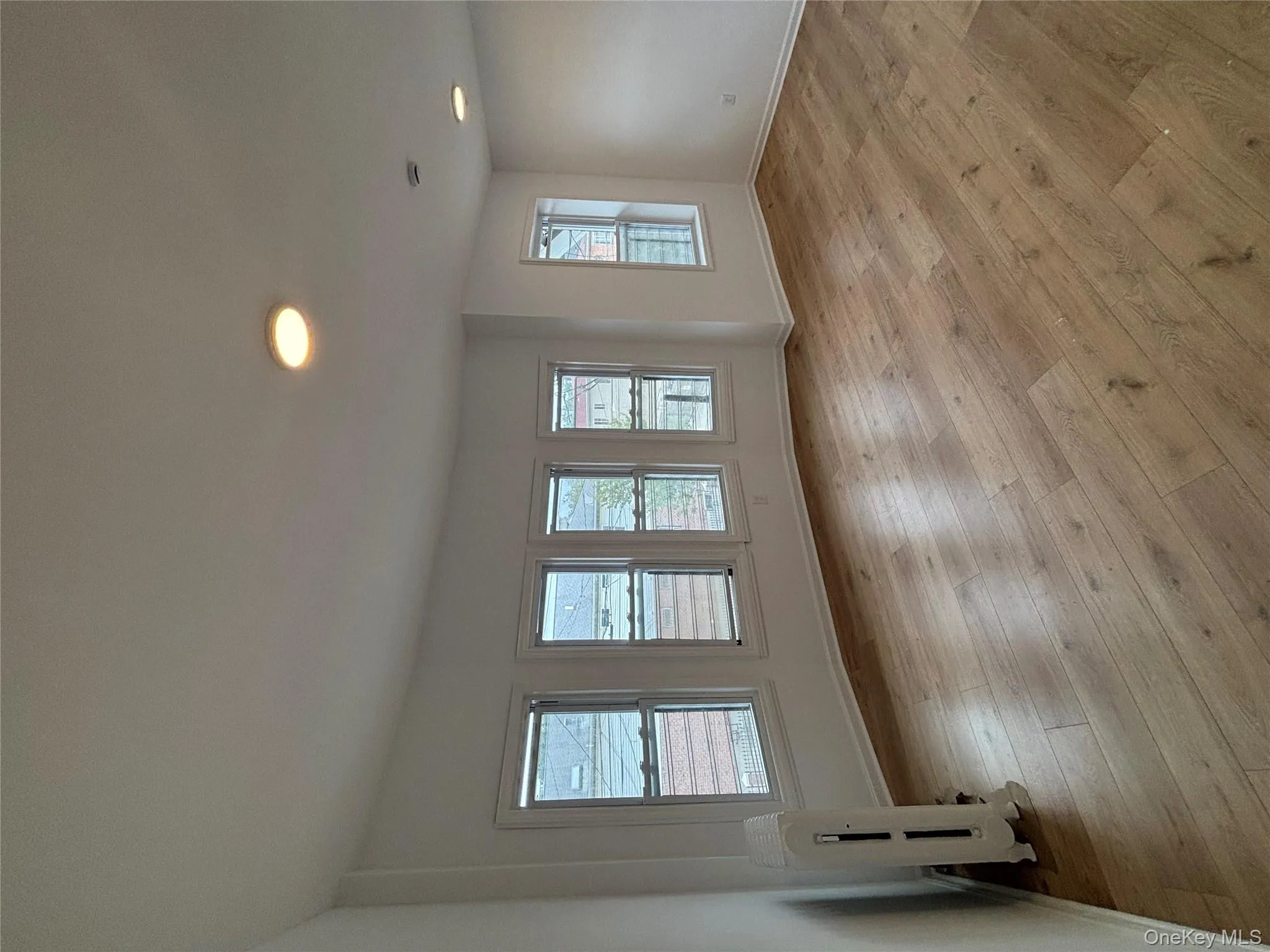 Empty room featuring light wood-style flooring, radiator heating unit, and recessed lighting Empty room featuring light wood-style flooring, radiator heating unit, and recessed lighting