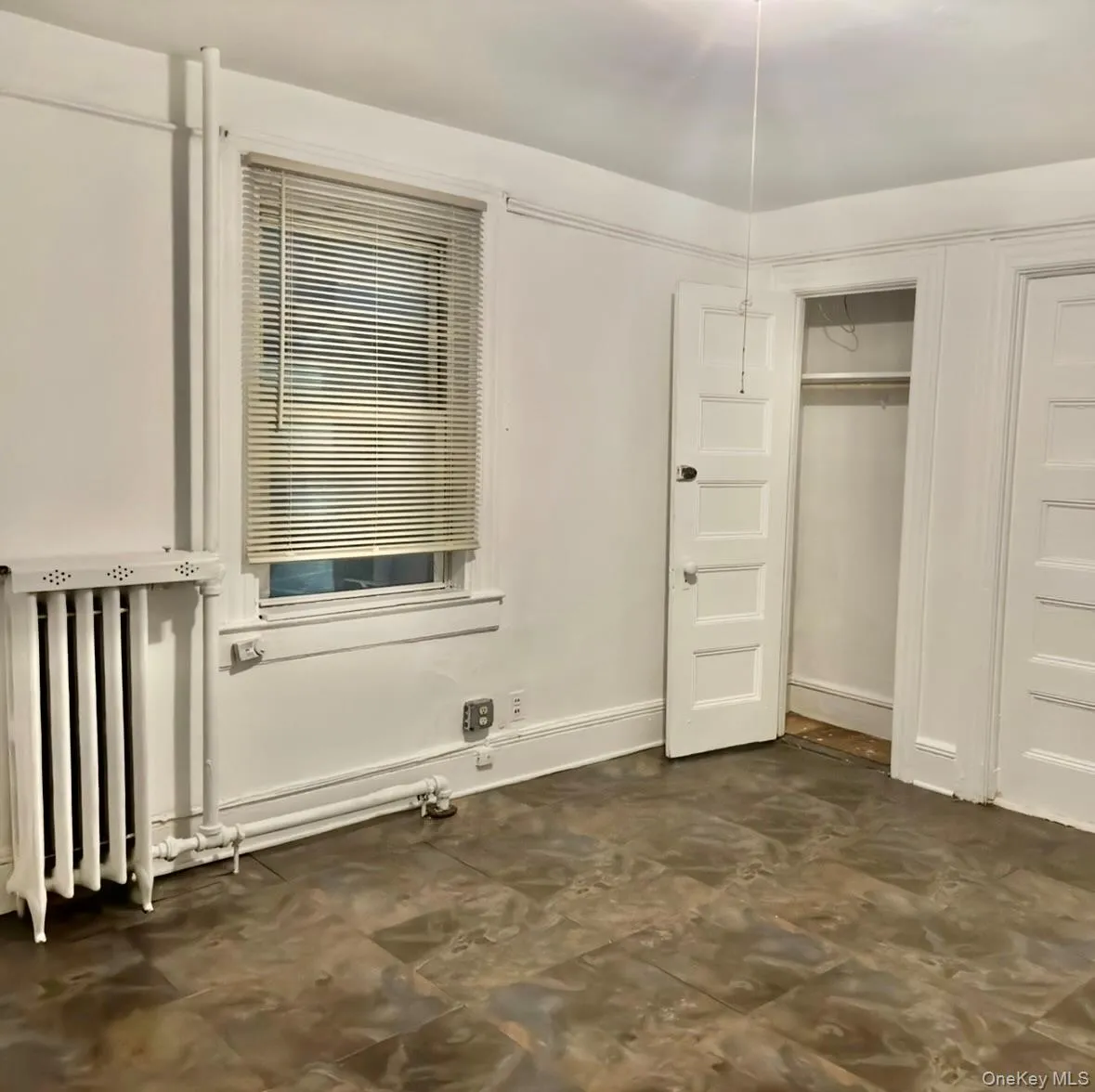 Unfurnished bedroom with radiator heating unit and a closet Unfurnished bedroom with radiator heating unit and a closet