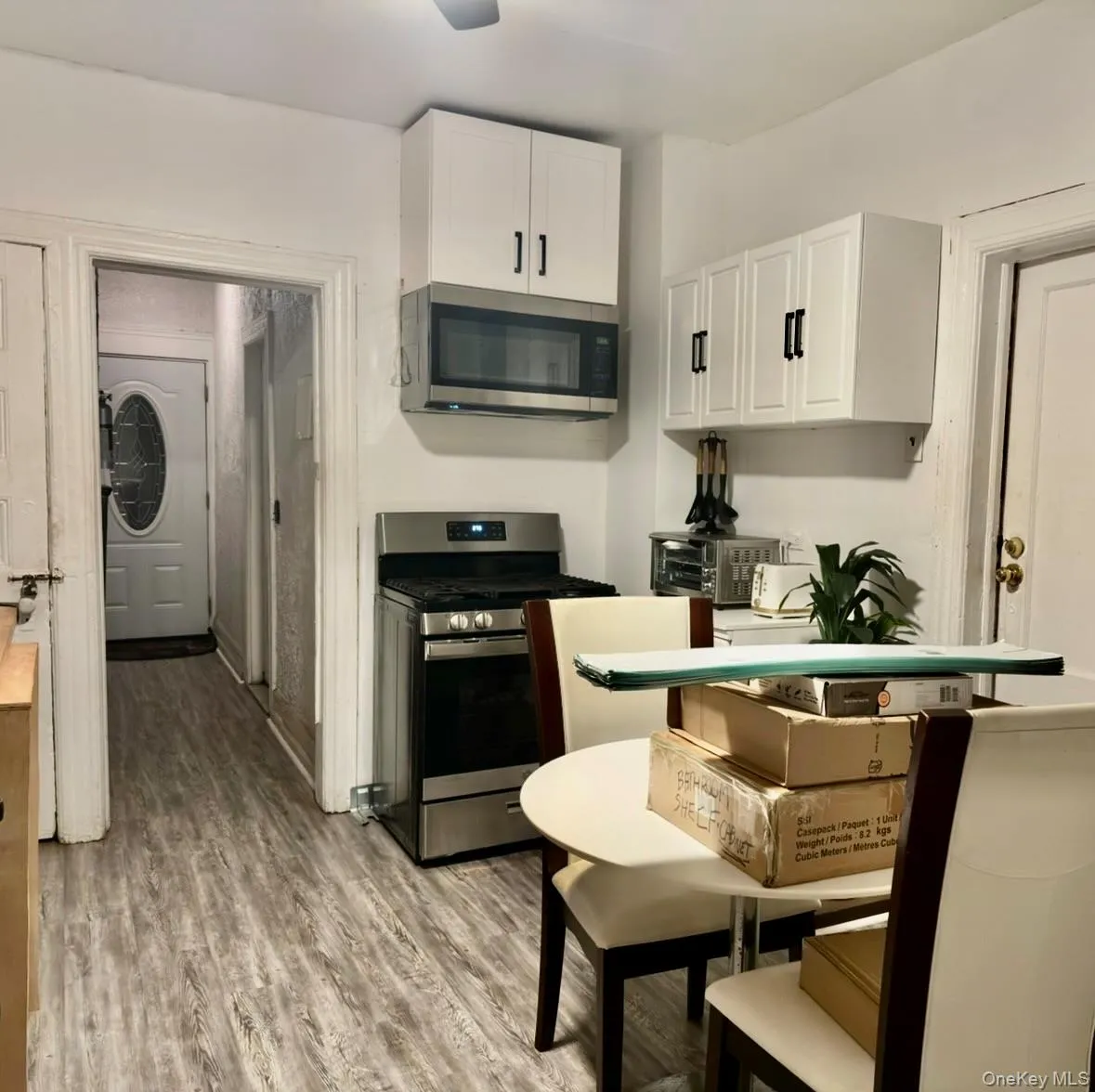 Kitchen with stainless steel appliances, white cabinetry, and light wood-type flooring Kitchen with stainless steel appliances, white cabinetry, and light wood-type flooring
