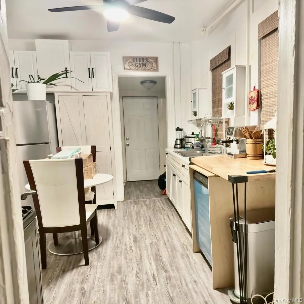 Kitchen with white cabinetry, wood counters, freestanding refrigerator, light wood-style flooring, and ceiling fan Kitchen with white cabinetry, wood counters, freestanding refrigerator, light wood-style flooring, and ceiling fan