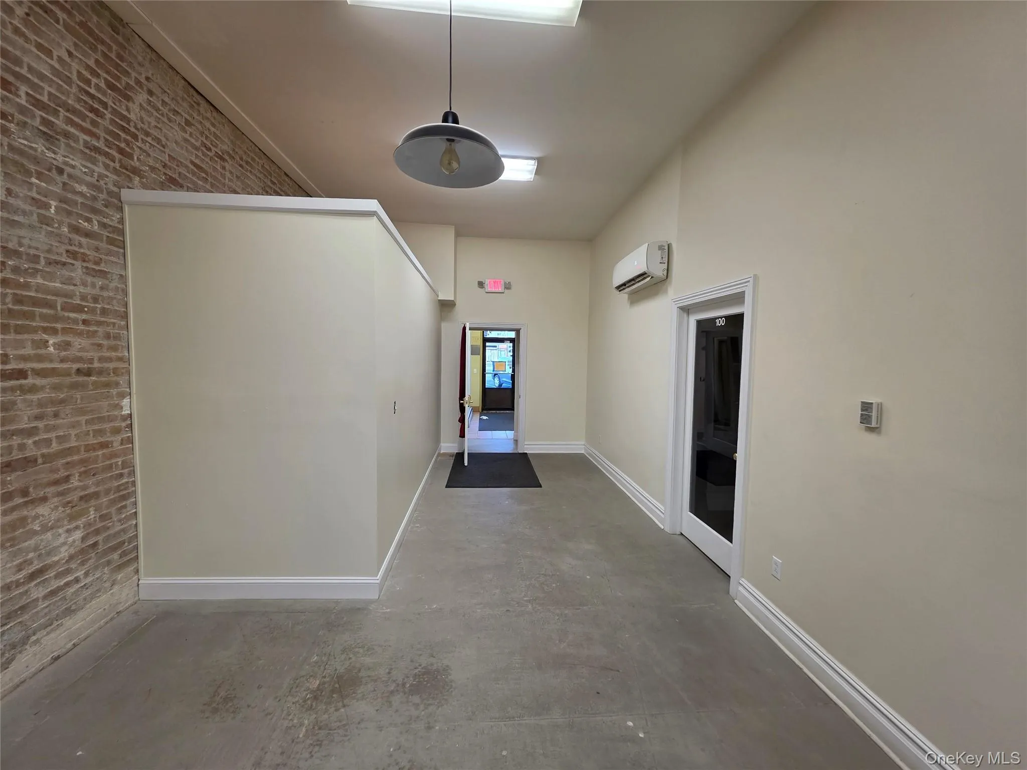Hallway featuring brick wall and concrete flooring Hallway featuring brick wall and concrete flooring