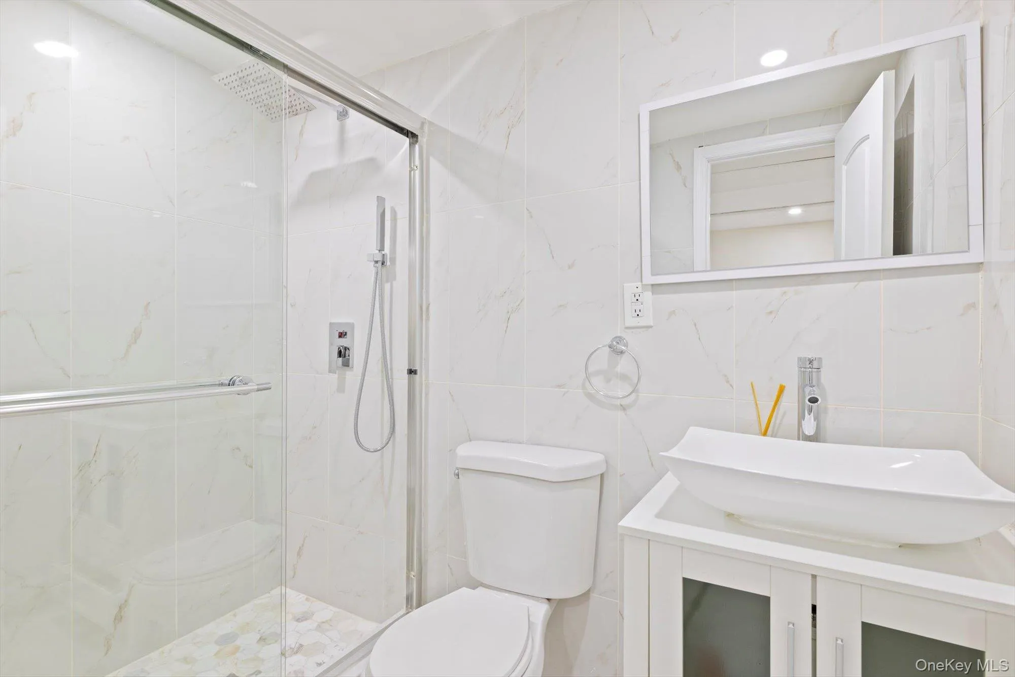 Full bath featuring vanity, a marble finish shower, and tile walls Full bath featuring vanity, a marble finish shower, and tile walls