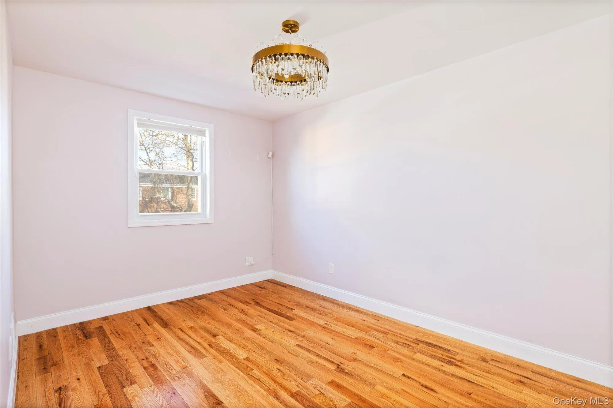 Unfurnished room with wood finished floors and a chandelier Unfurnished room with wood finished floors and a chandelier
