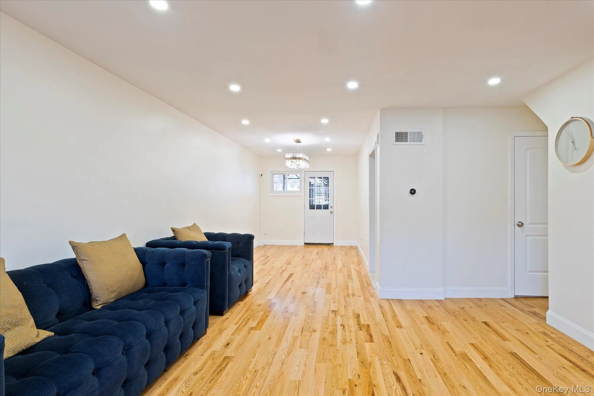 Living room featuring light wood-style flooring, recessed lighting, and a chandelier Living room featuring light wood-style flooring, recessed lighting, and a chandelier